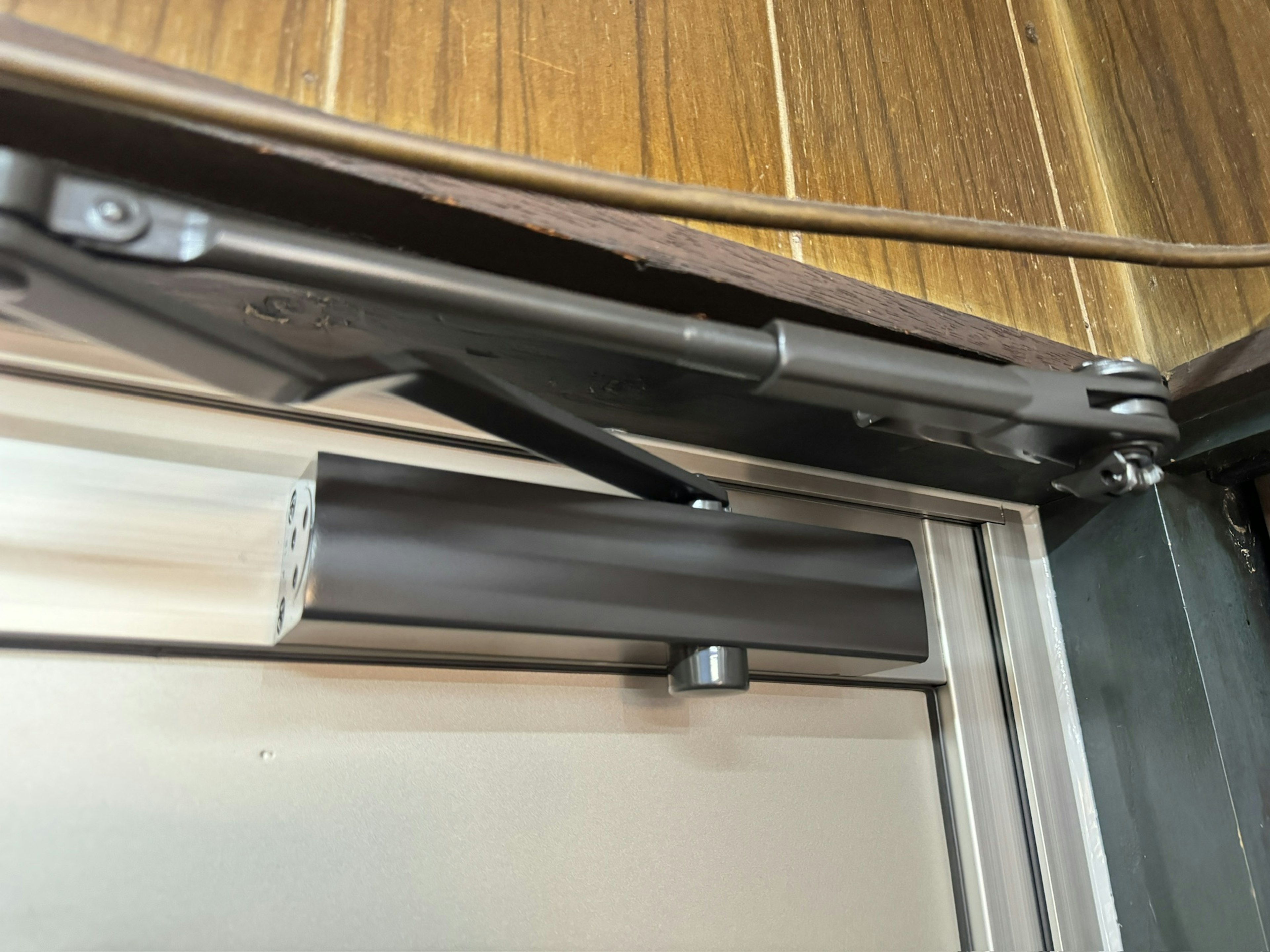 Close-up of a door closer installation with metal components