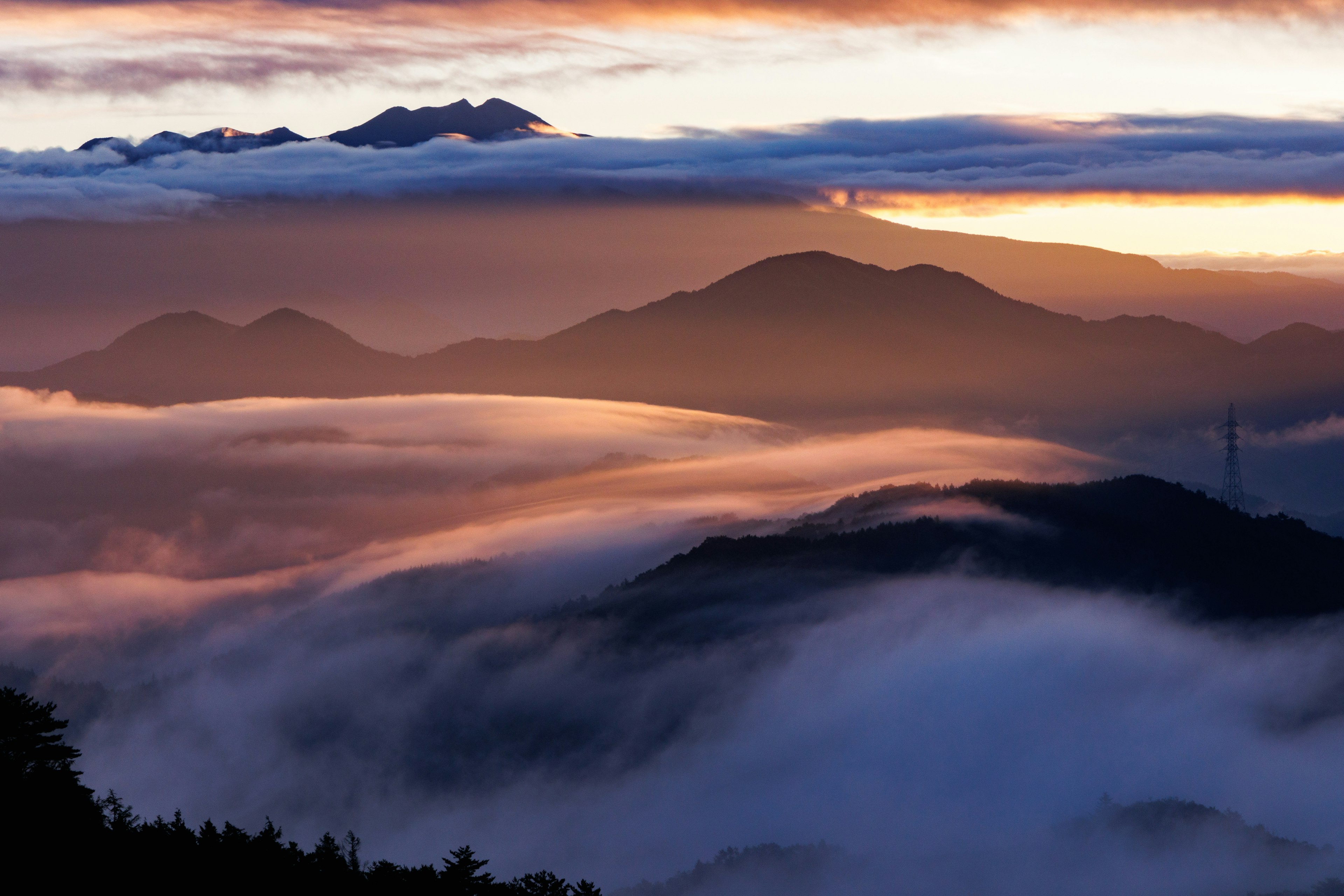 Paisaje montañoso envuelto en niebla con un atardecer colorido