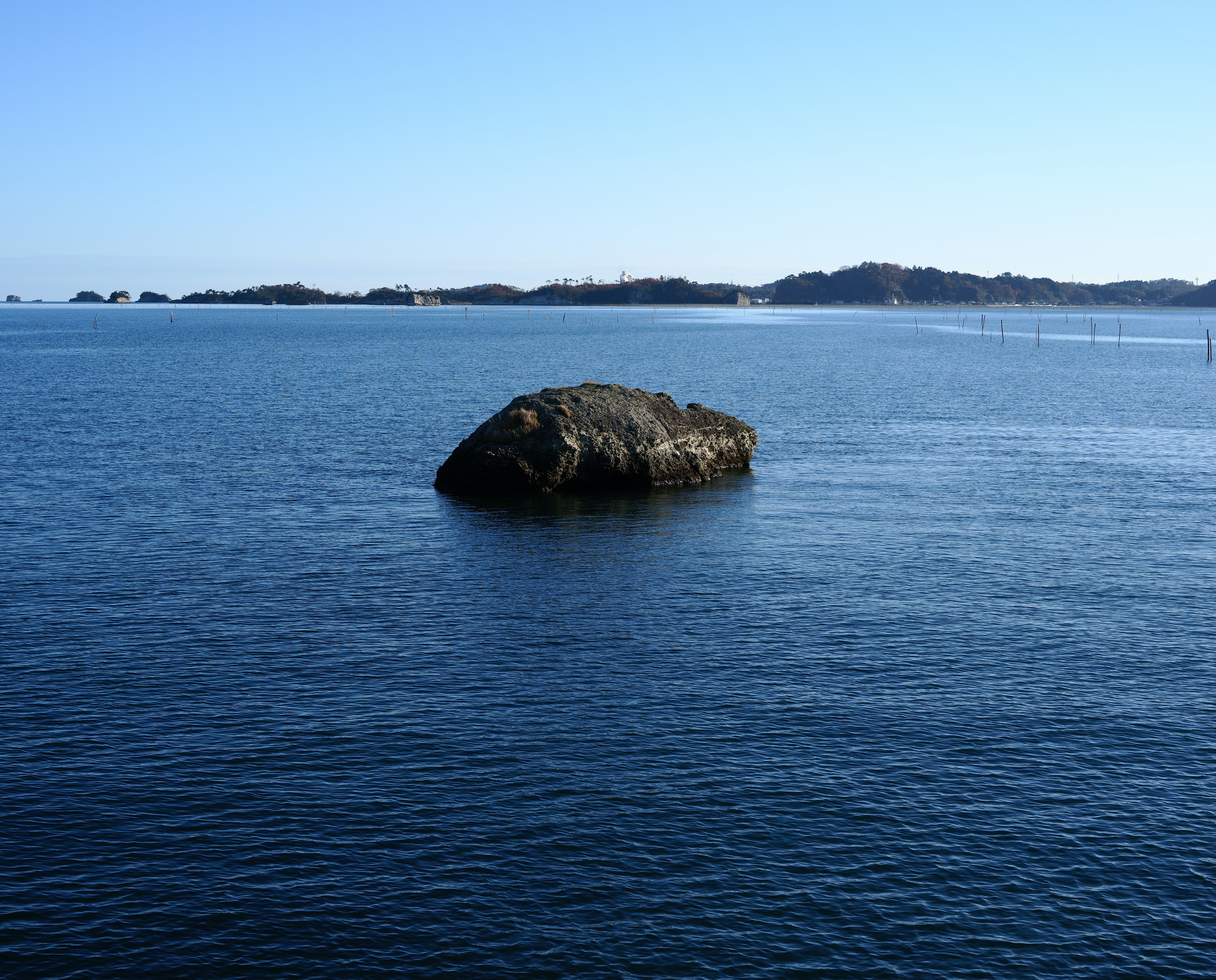 蓝色海洋中漂浮着一块大石头和遥远的岛屿