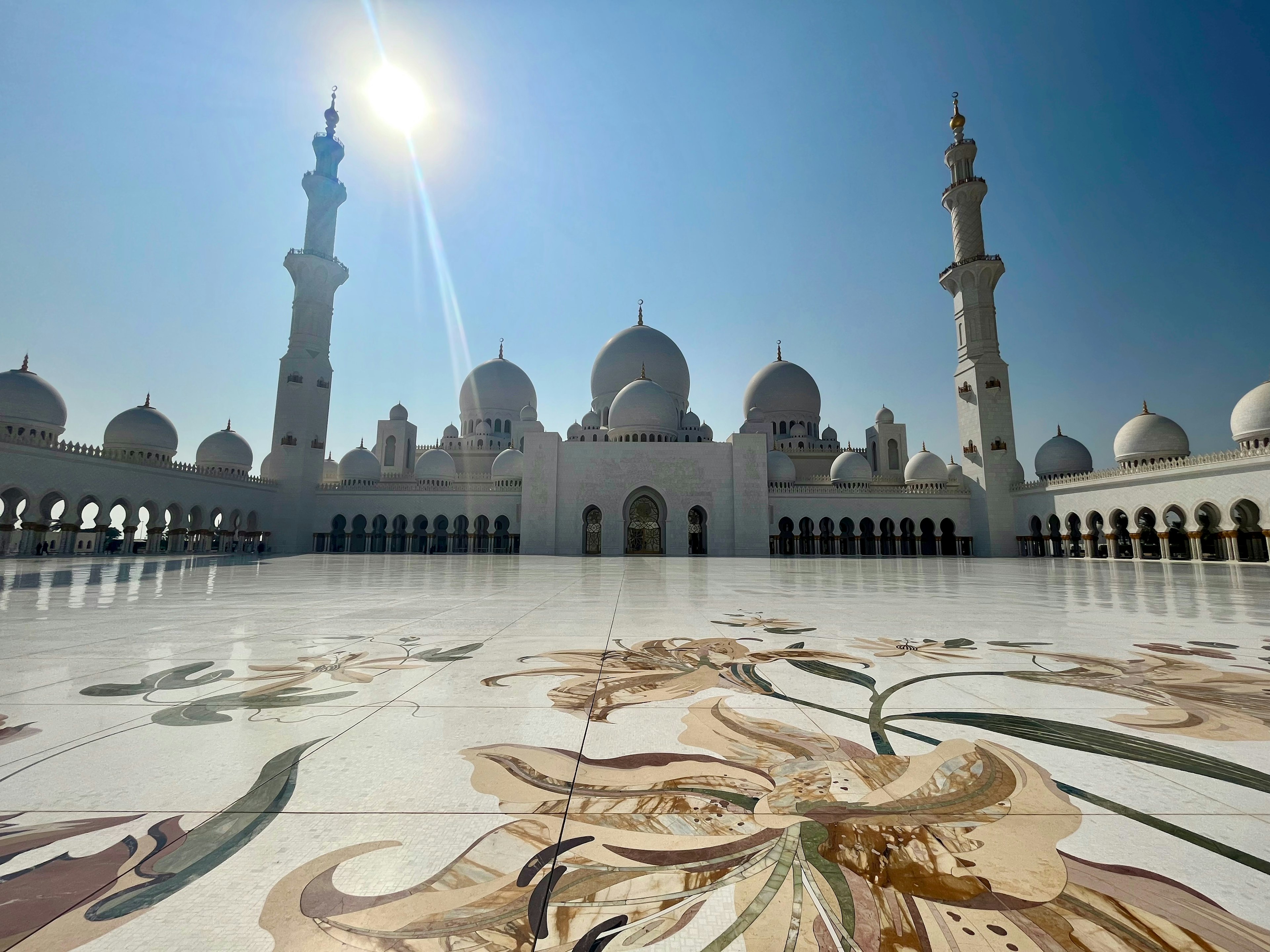 Stunning white mosque exterior with decorative tiled floor