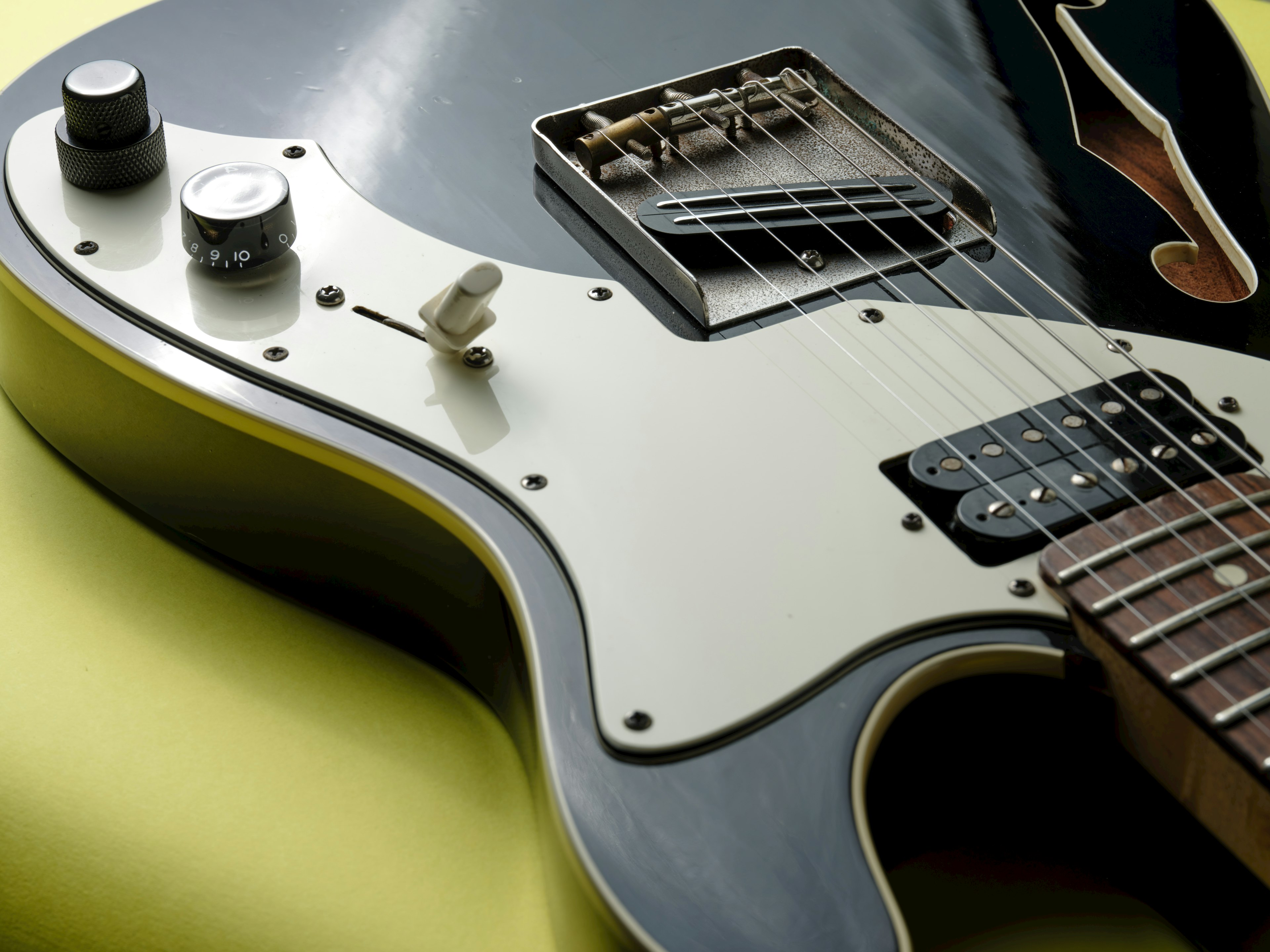 Close-up image of a black and cream electric guitar featuring unique body design and knobs