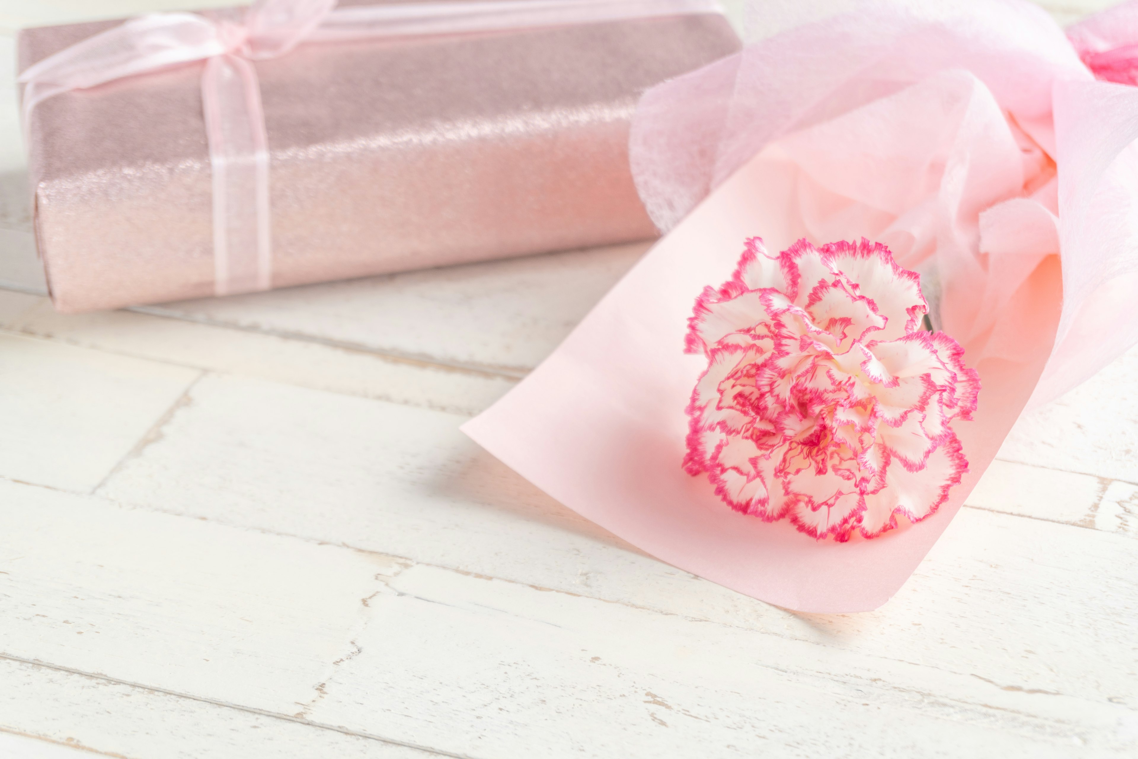 Caja de regalo con envoltura rosa y una flor de clavel