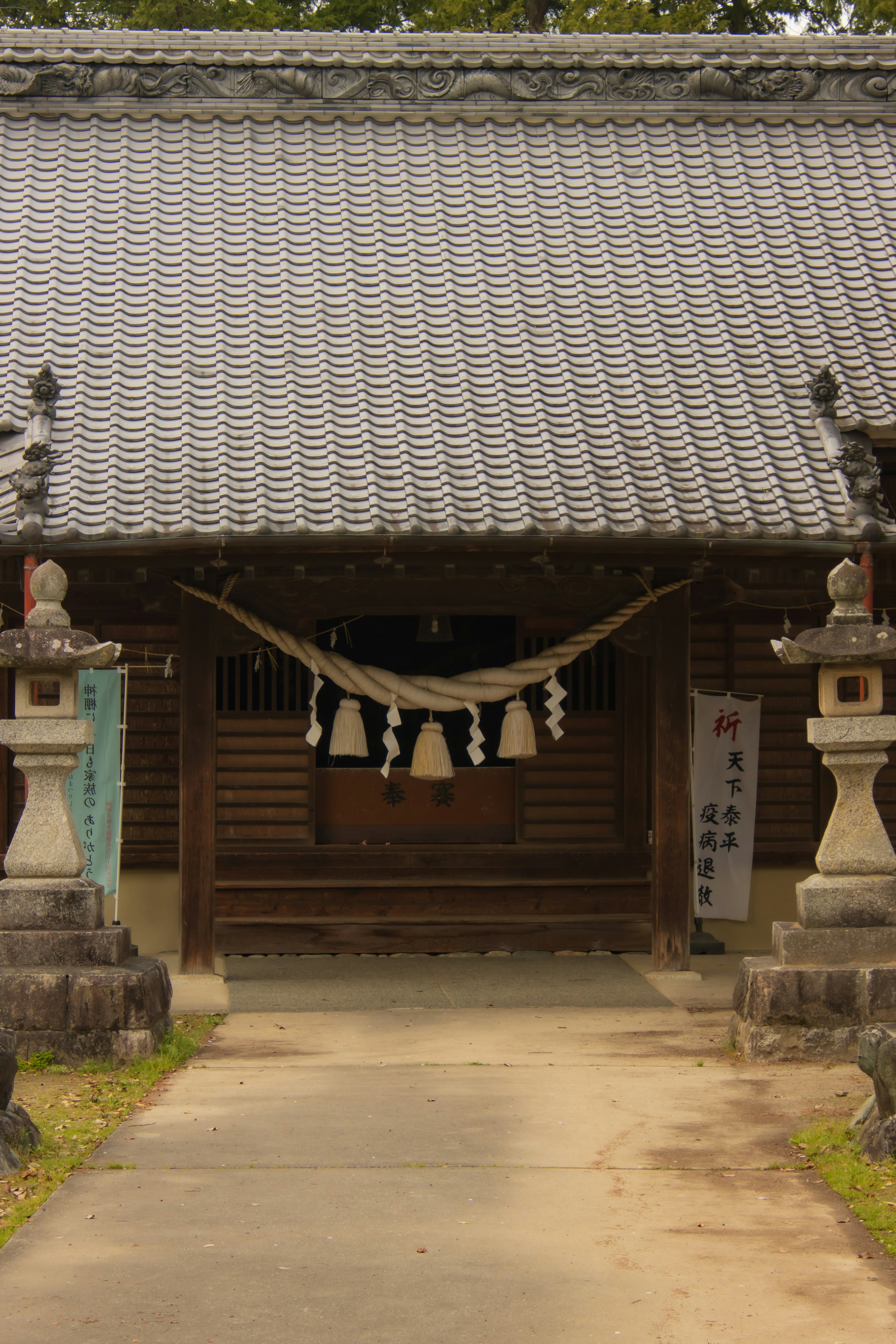 Eingang eines traditionellen japanischen Tempels mit Ziegeldach und Steinstatuen