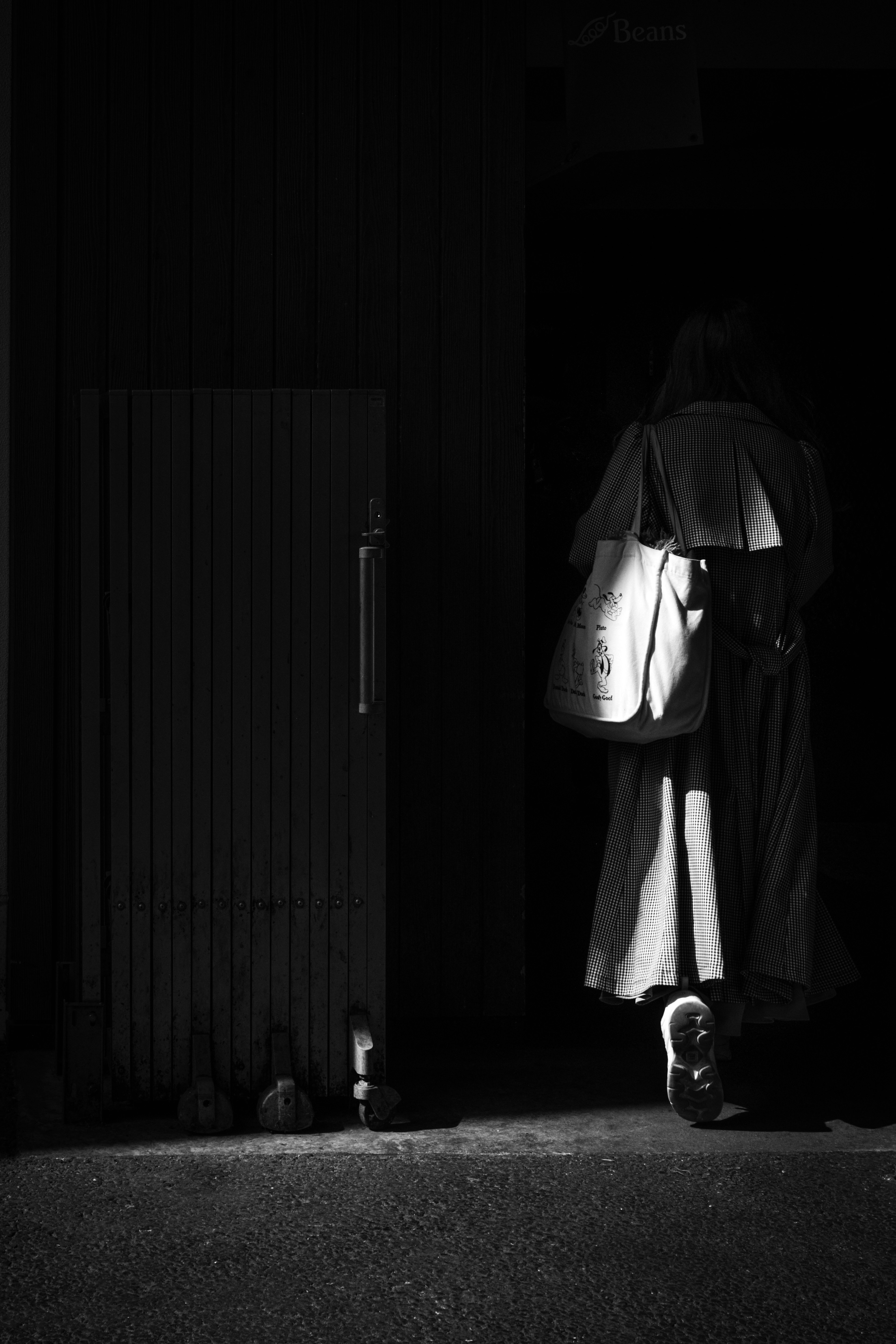 A woman walking with a white bag against a dark background