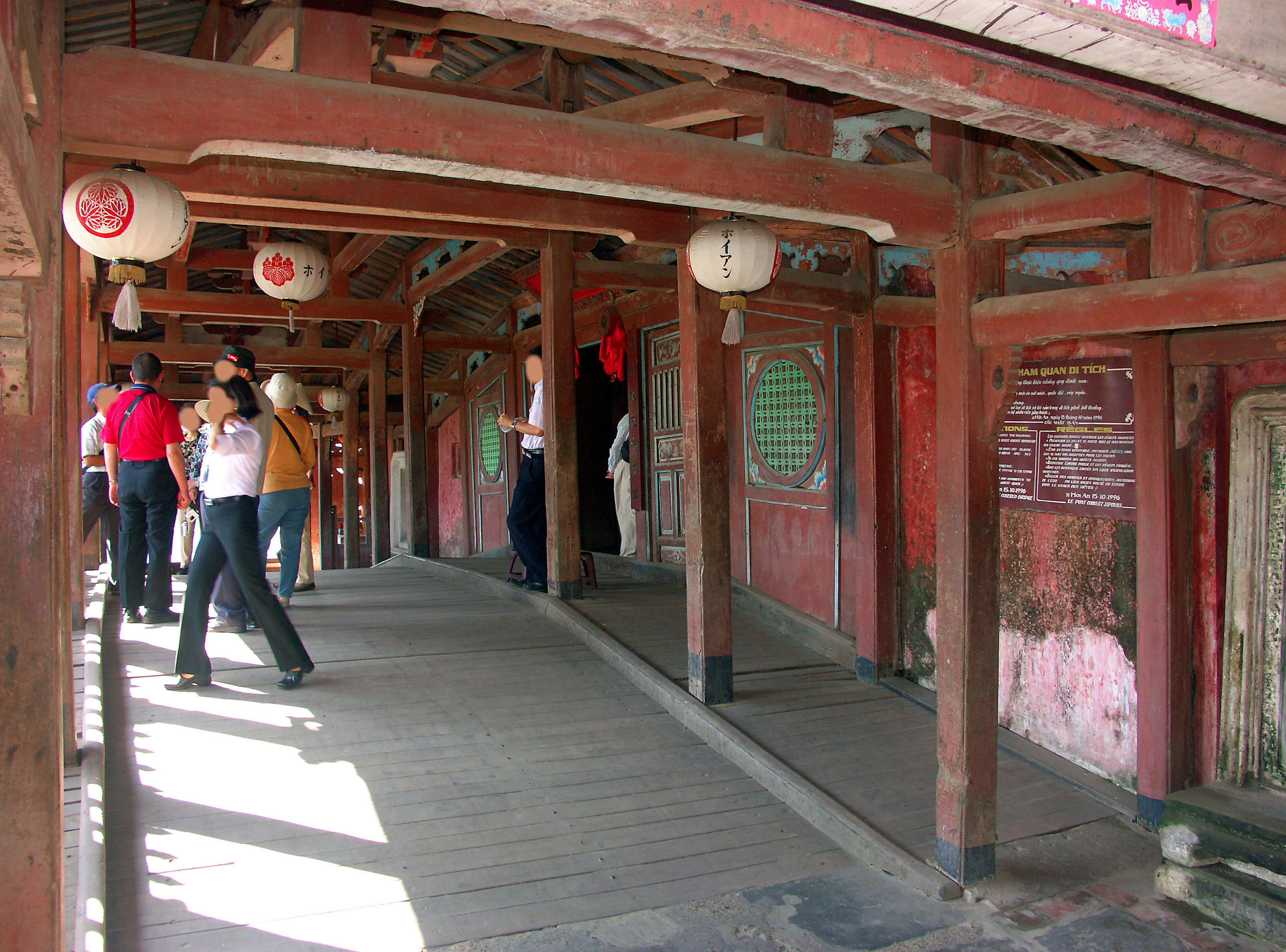 Interior view of an old building with people and hanging red lanterns in the corridor