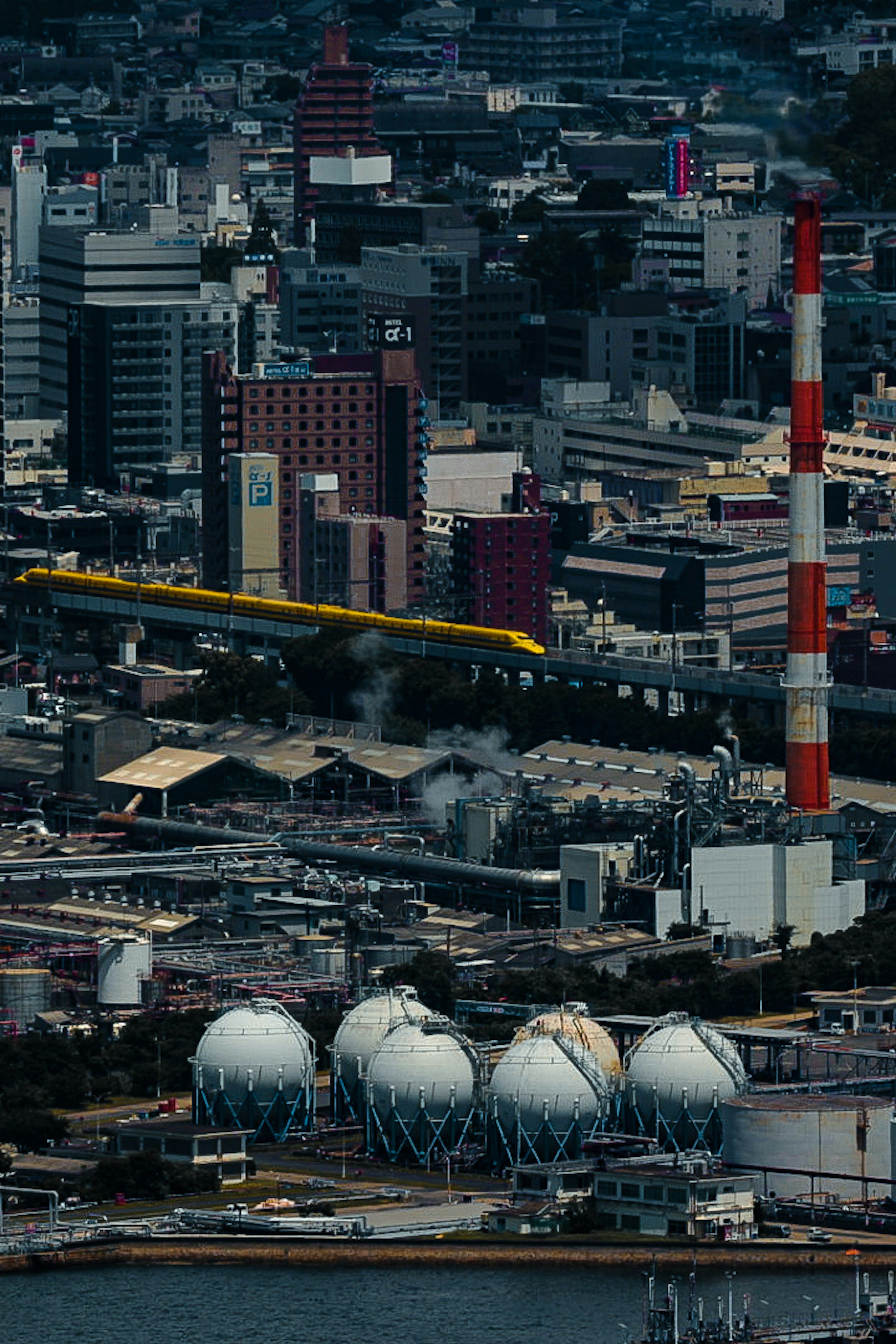 城市景觀，包含高樓大廈和工業煙囪 黃色火車在軌道上行駛