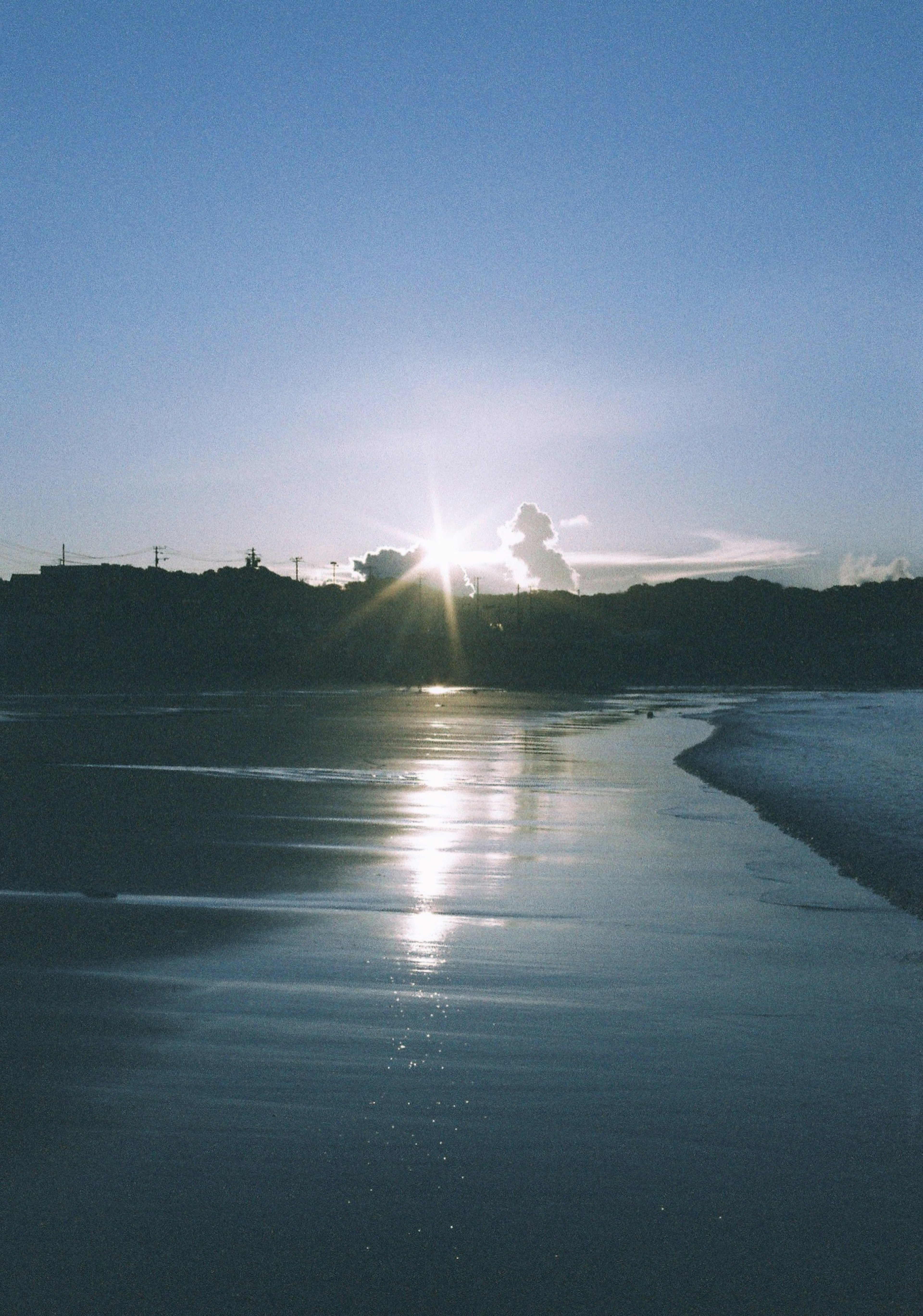 Hermoso paisaje del atardecer reflejándose en la costa con un cielo azul