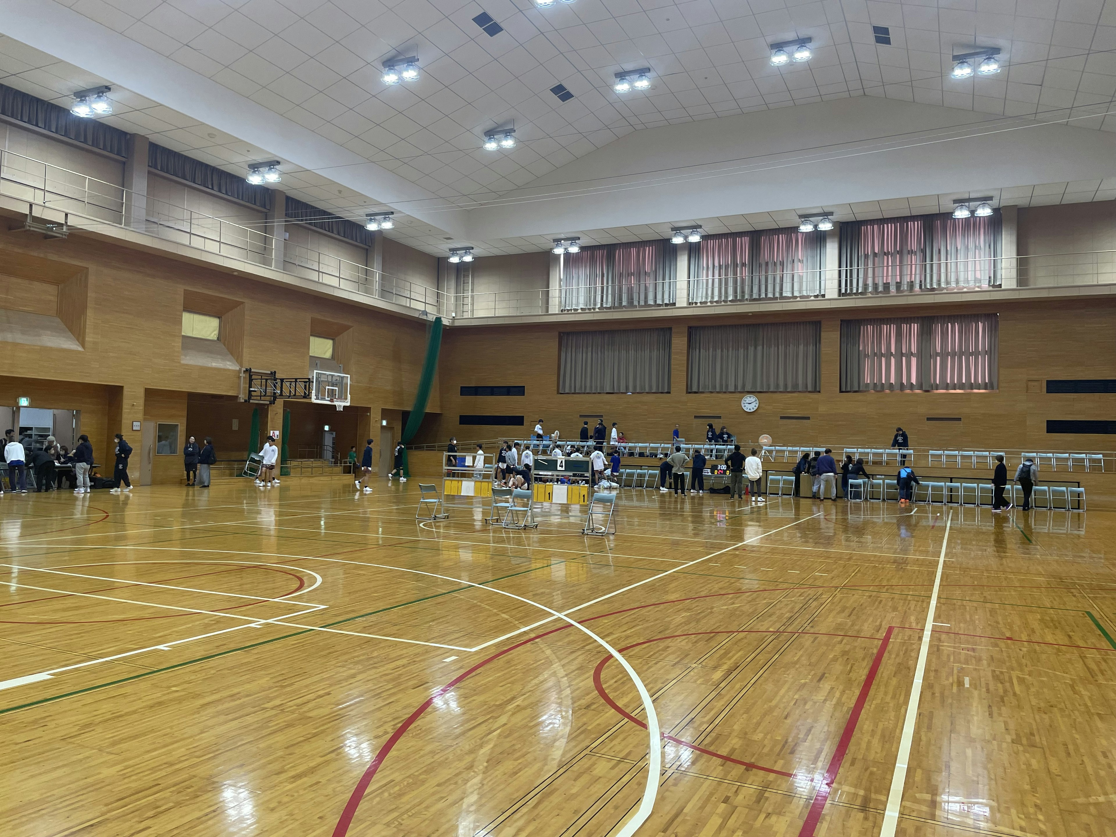 Spacious interior of a gymnasium featuring wooden flooring and visible basketball court