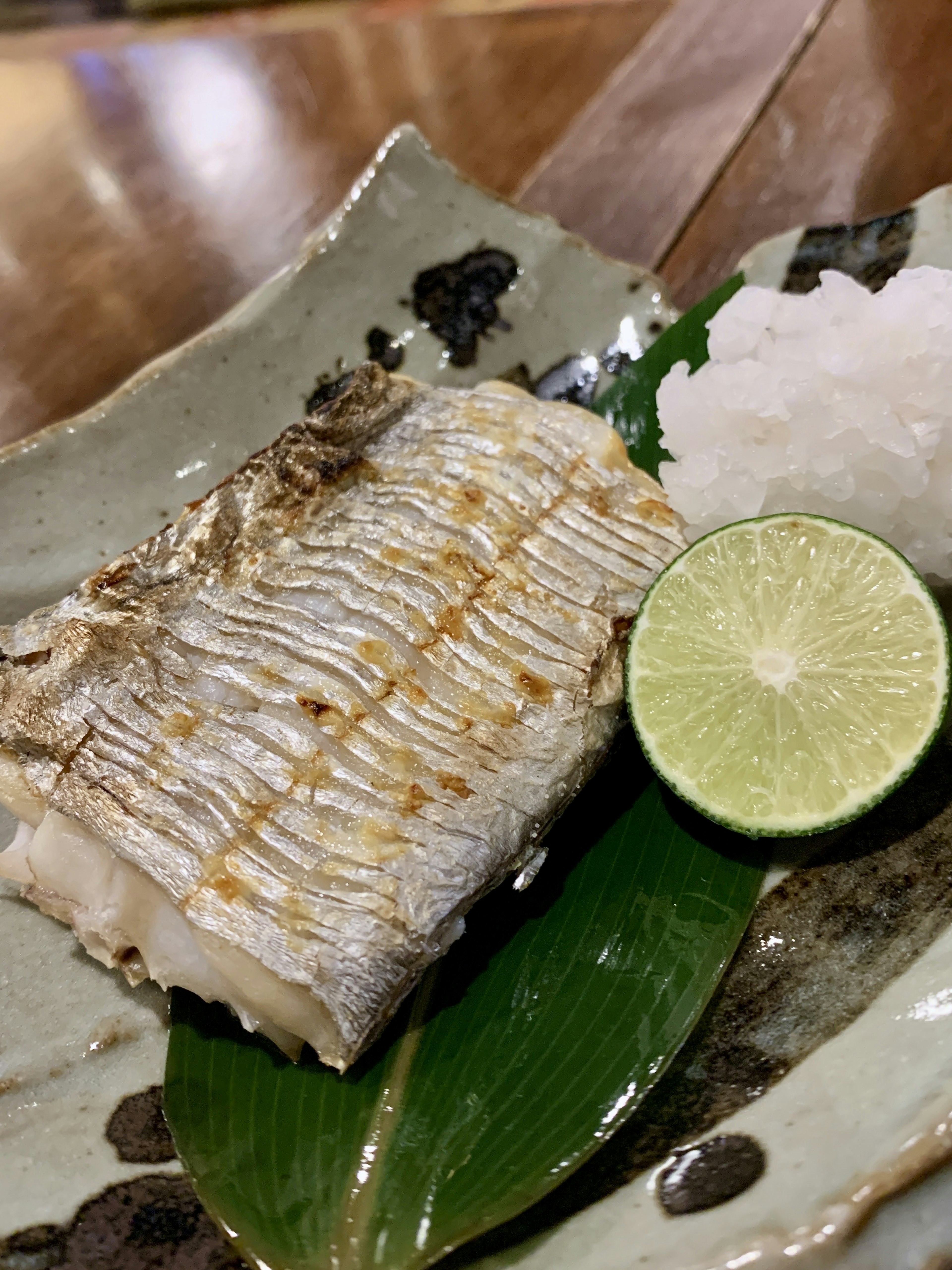 Pesce grigliato servito su un piatto con lime e daikon grattugiato