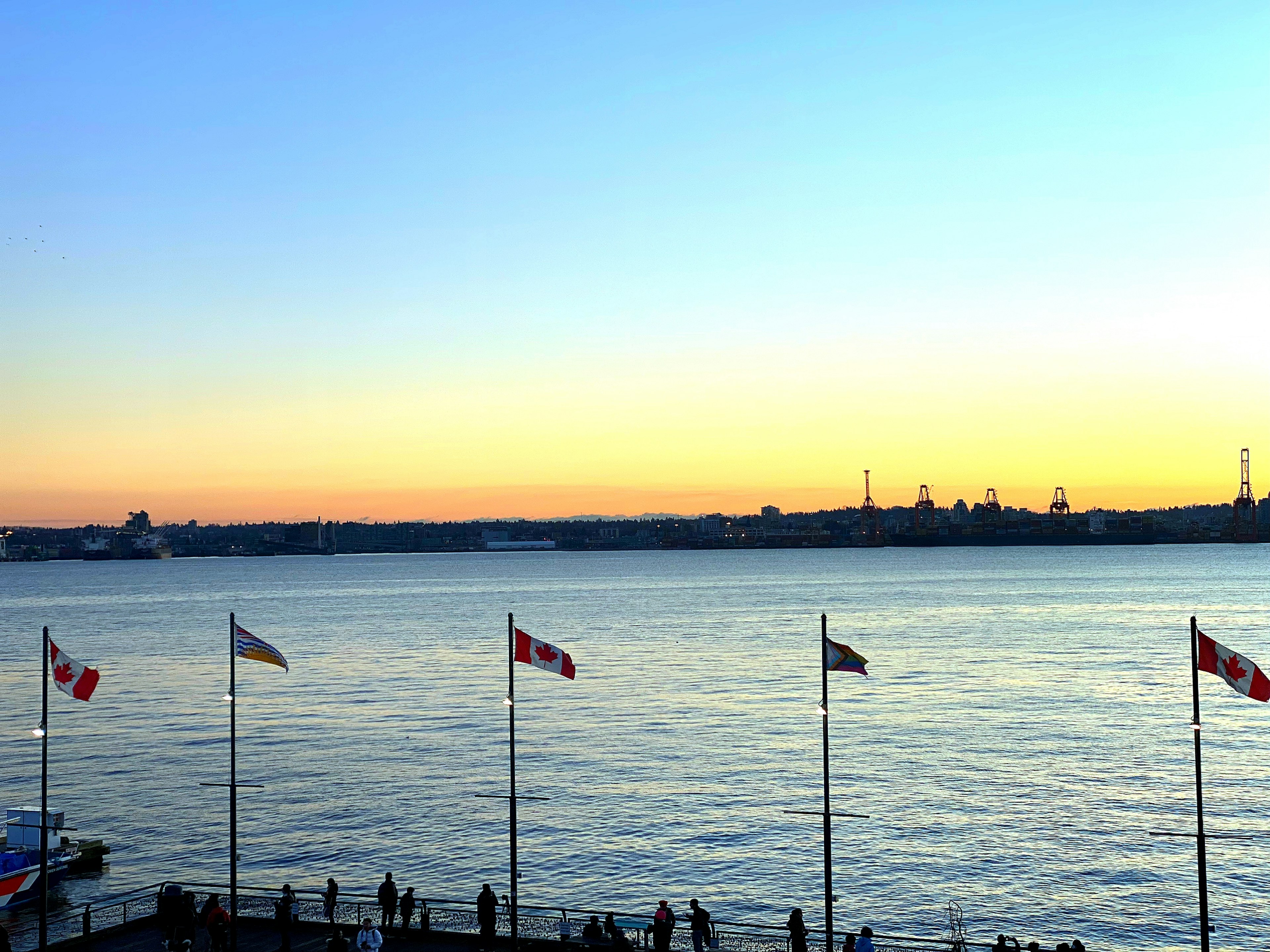 Tramonto sul mare con bandiere e skyline della città