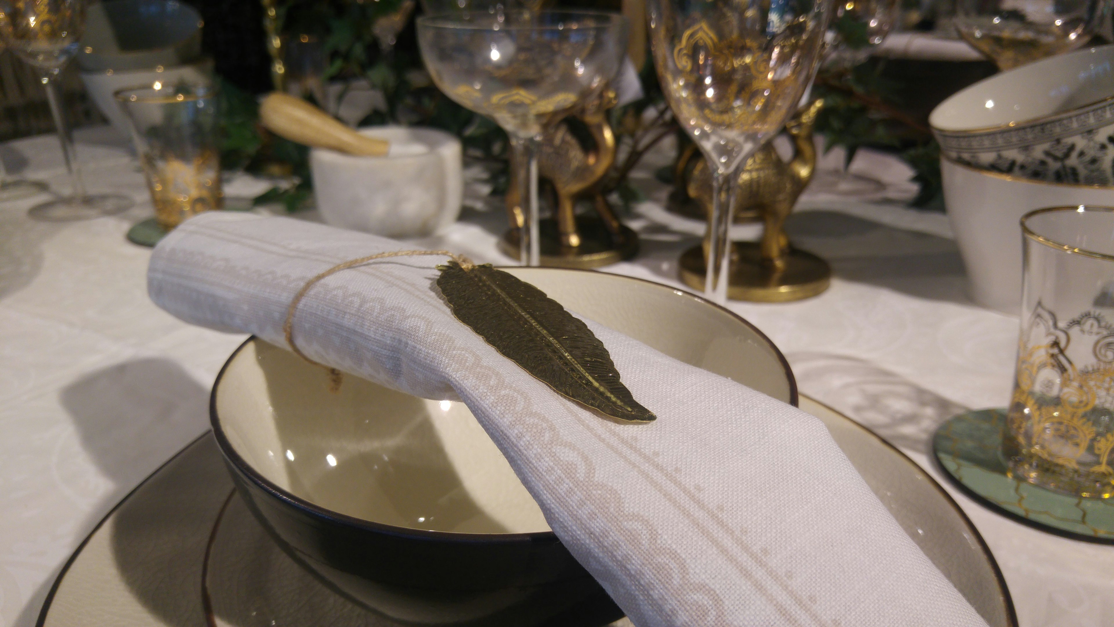 Gros plan d'une table dressée avec une serviette blanche et une feuille, vaisselle élégante et verres