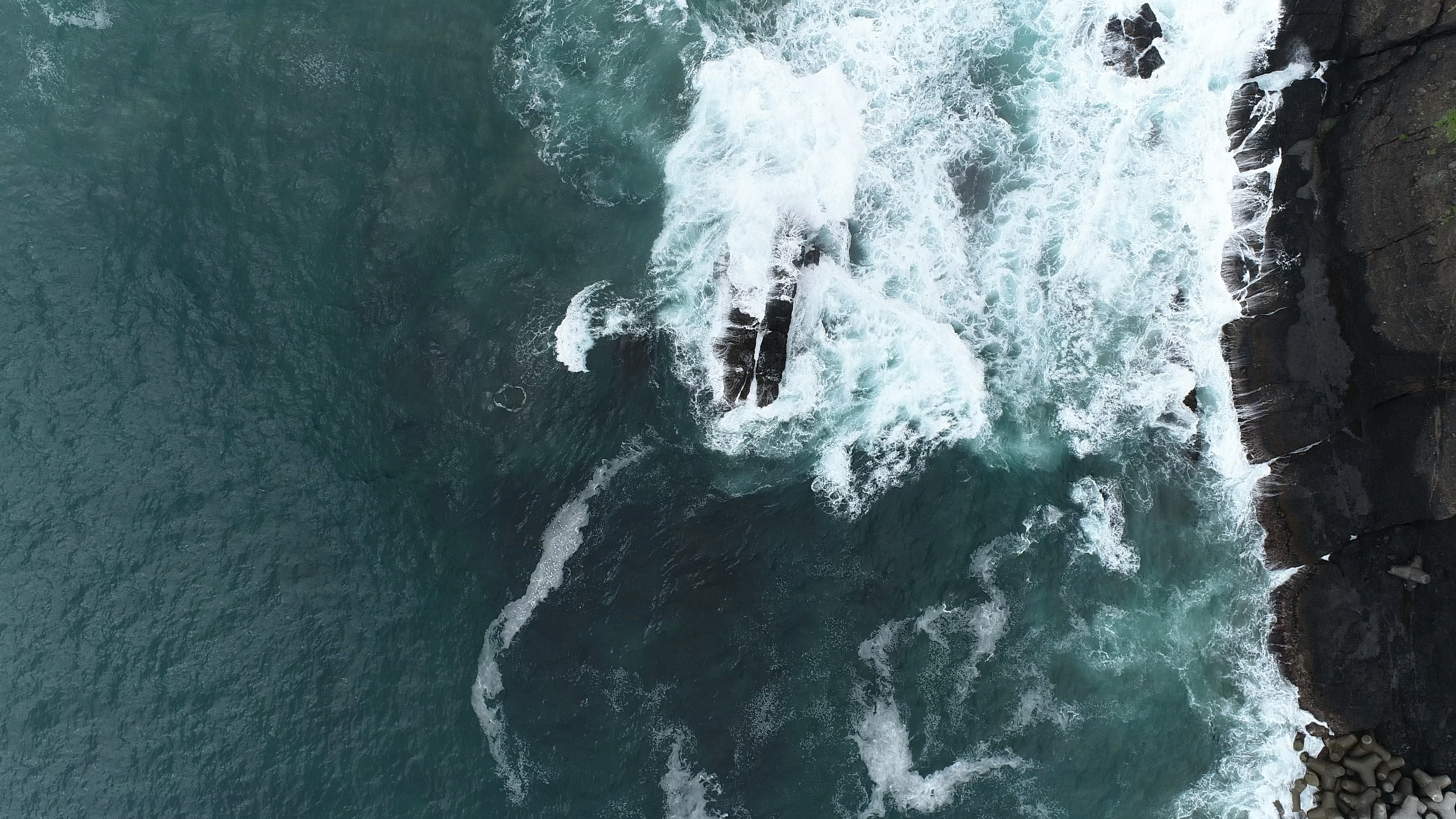 Aerial view of ocean waves crashing against rocks