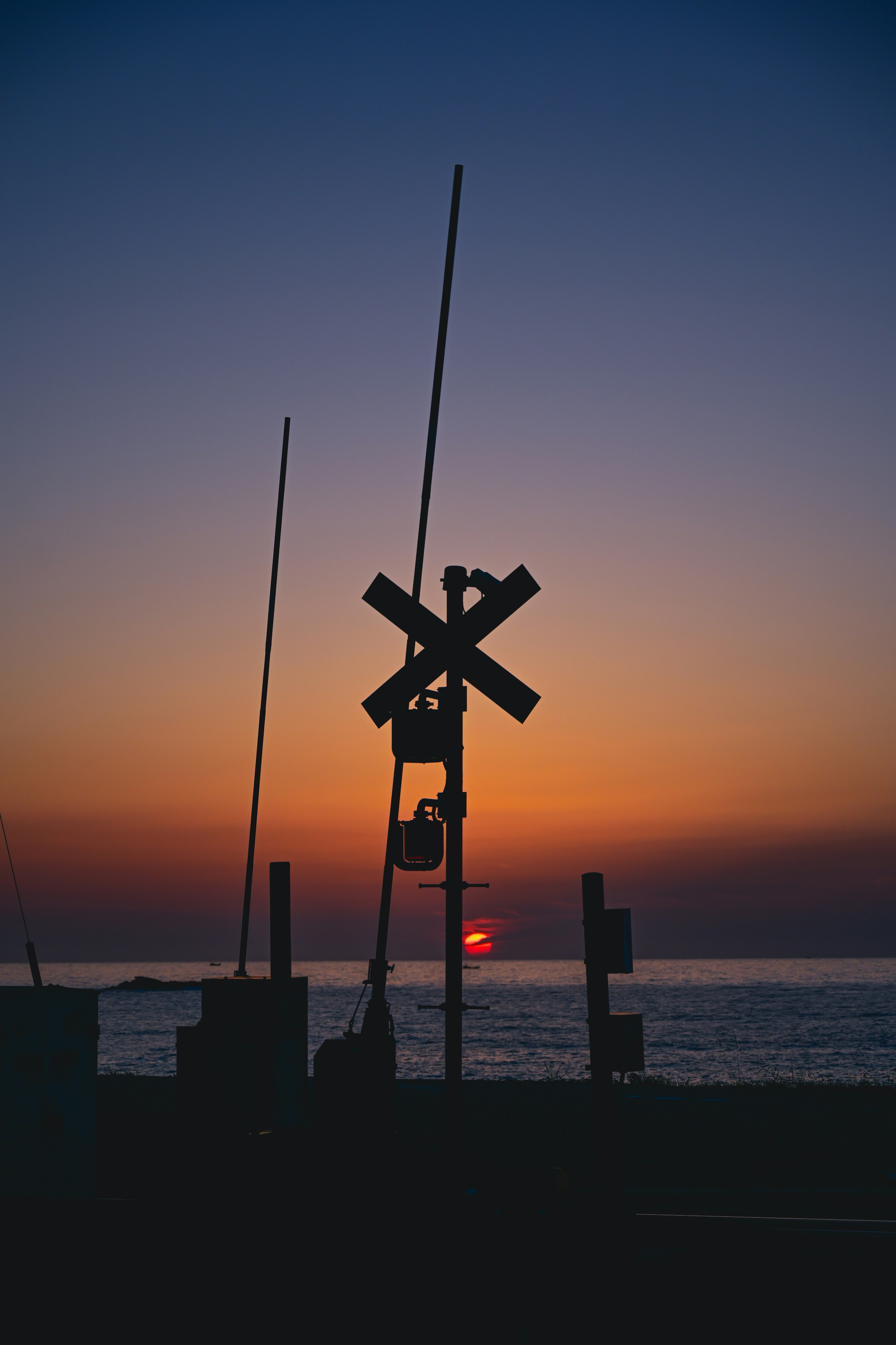 Silhouette of a railroad crossing against a sunset