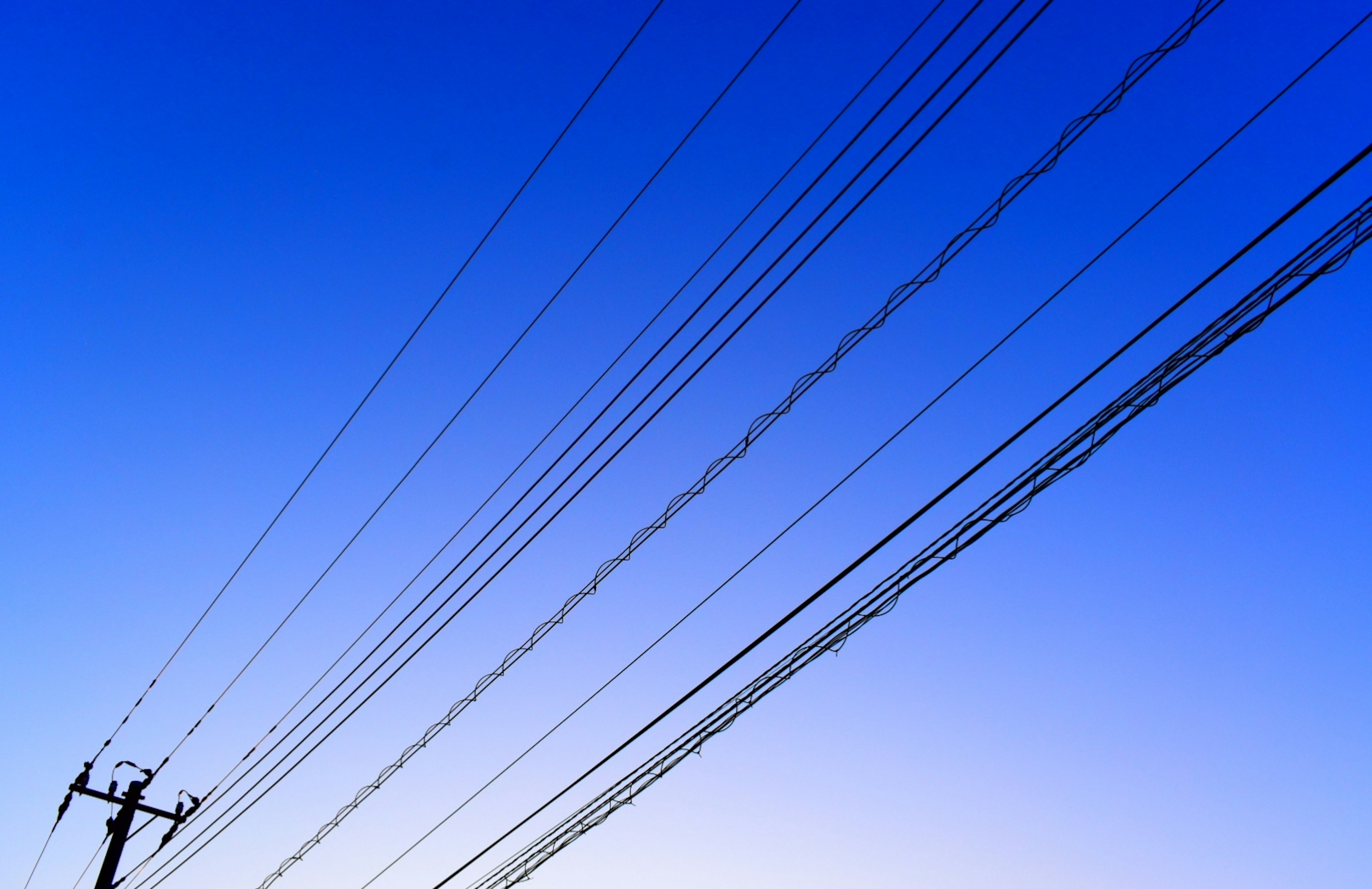 Silhouette of power lines against a blue sky