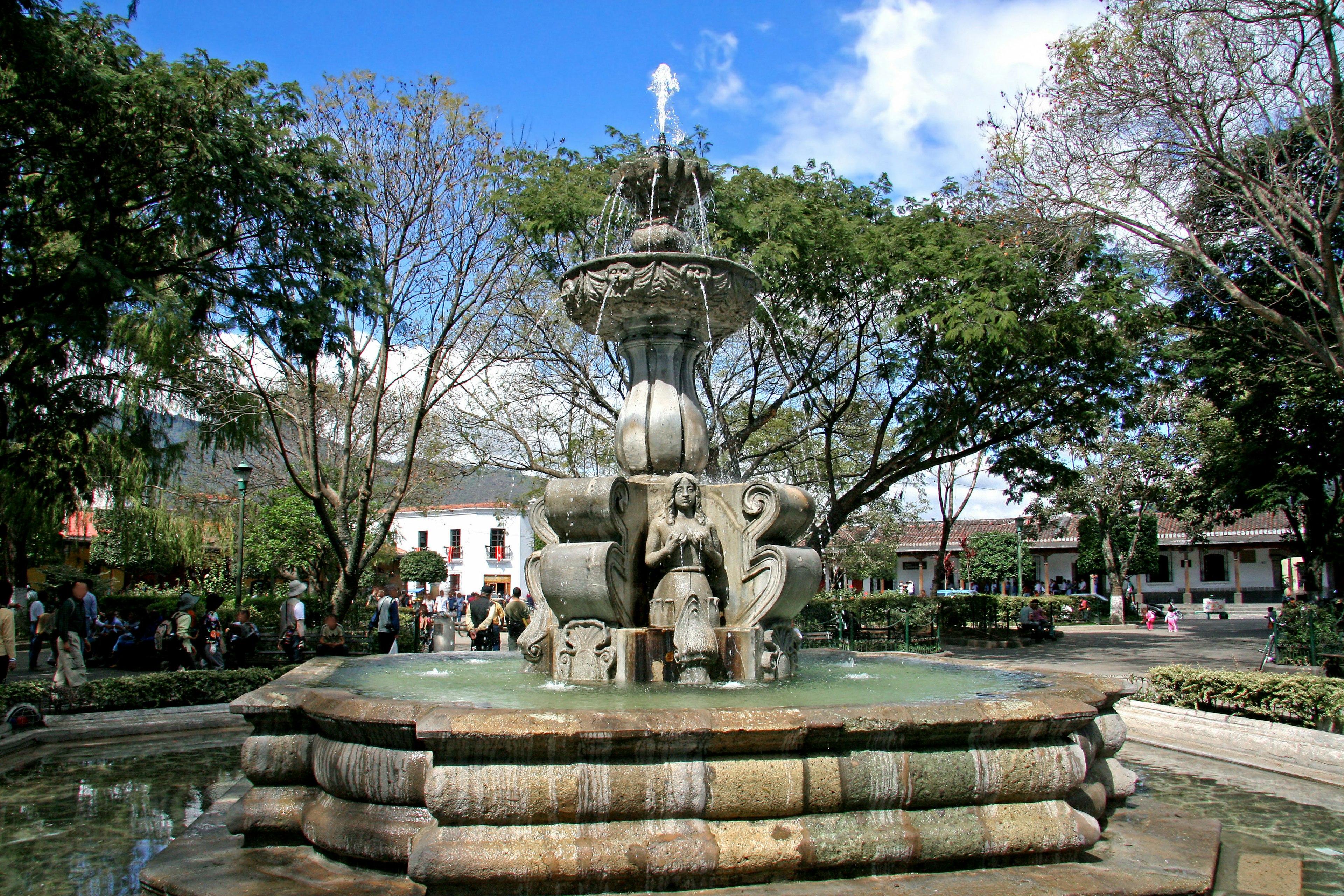 A beautiful fountain surrounded by lush trees in a park