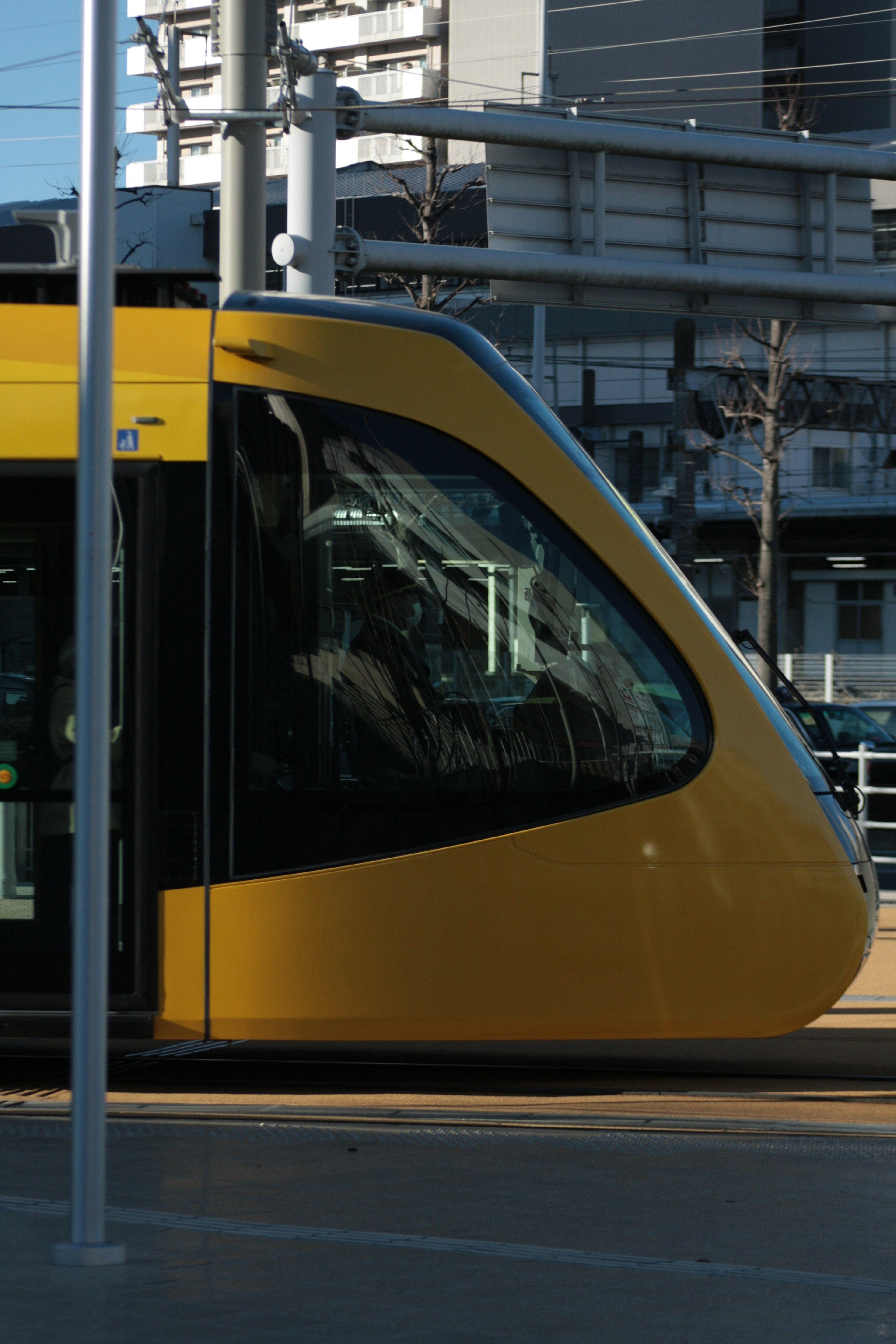 Tampak samping trem kuning di stasiun