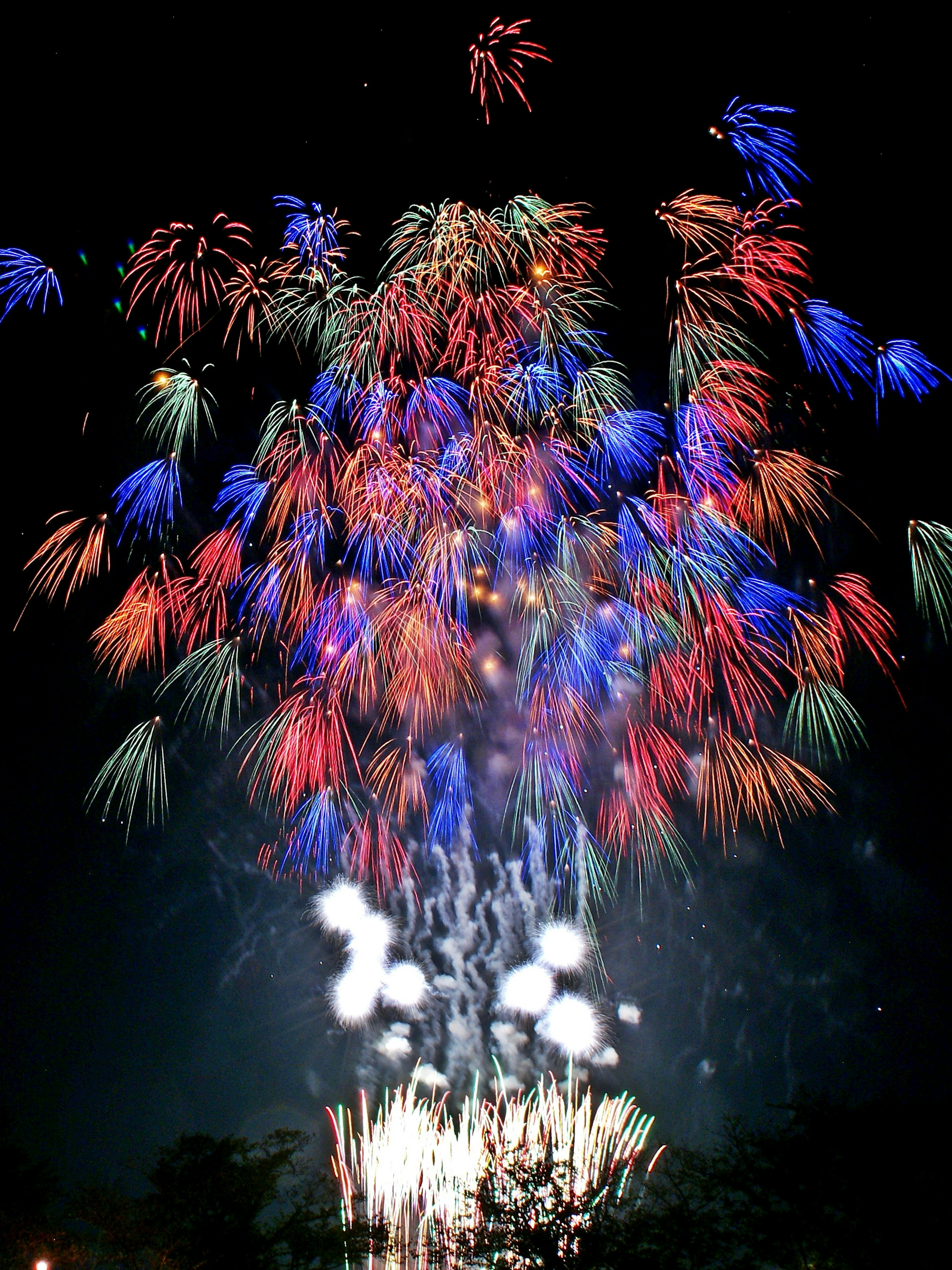 Vibrant fireworks display in the night sky with colorful bursts of red, blue, and green