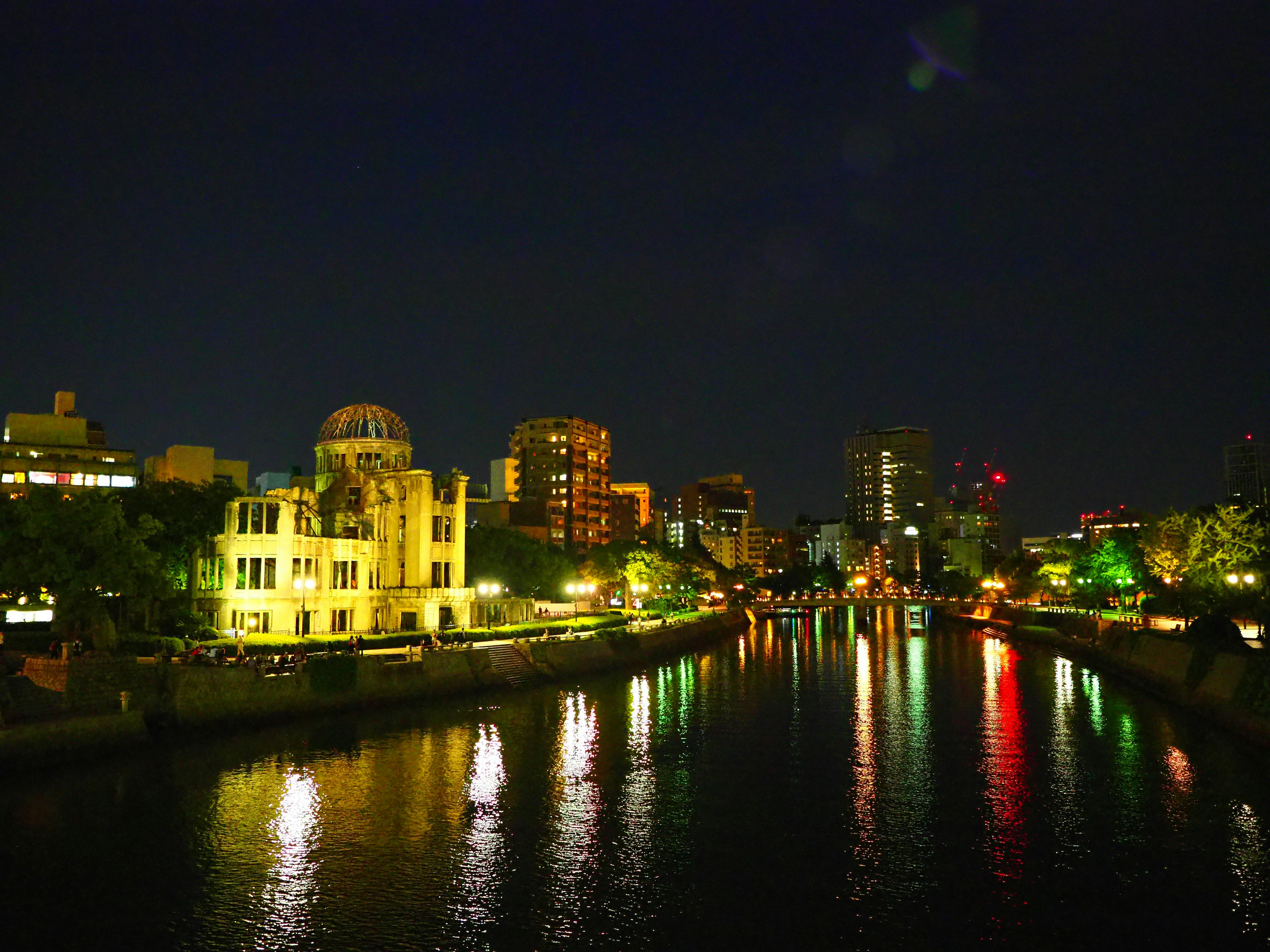 Vista nocturna de Hiroshima con luces coloridas reflejándose en el río