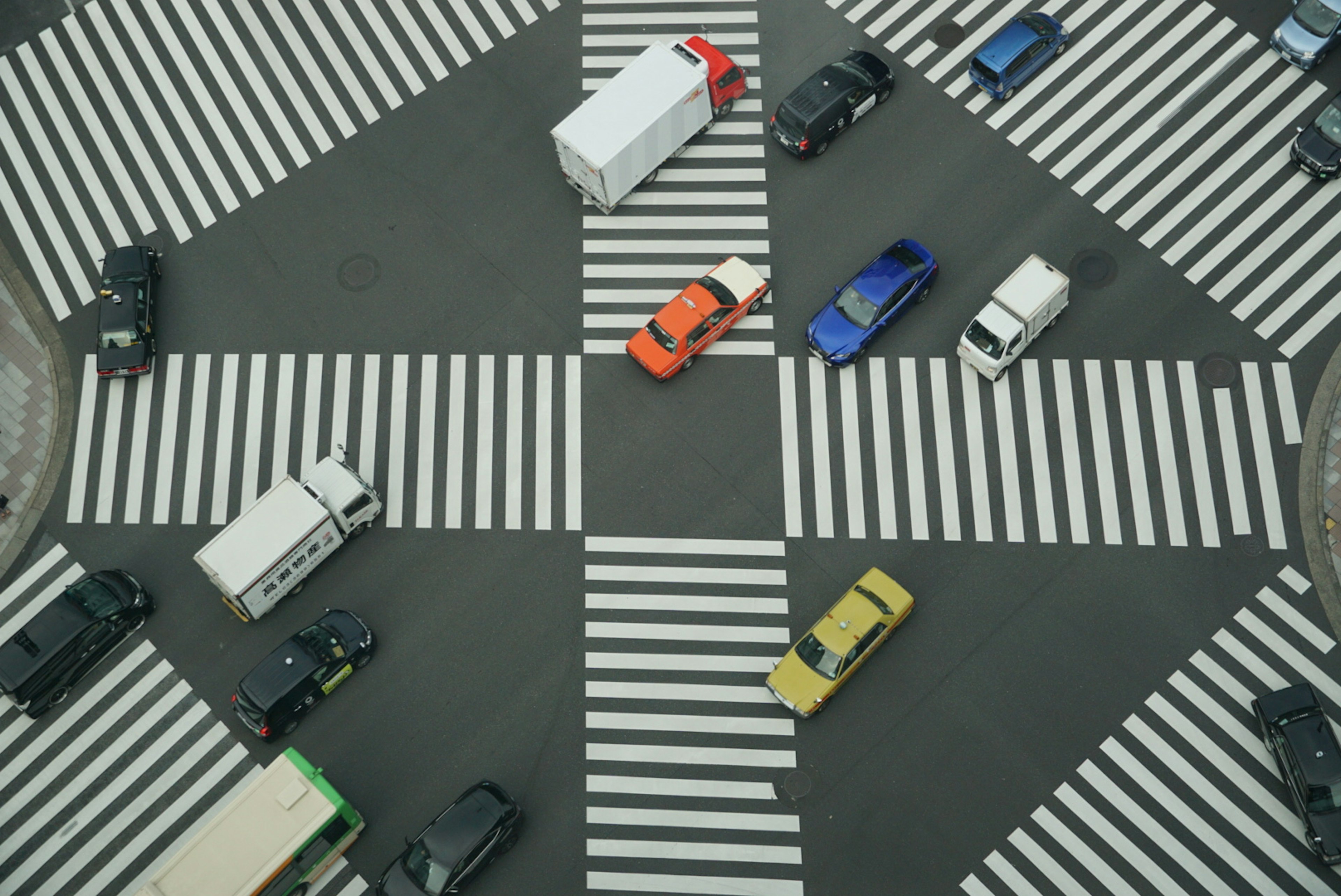 Vue aérienne d'une intersection avec divers véhicules colorés traversant