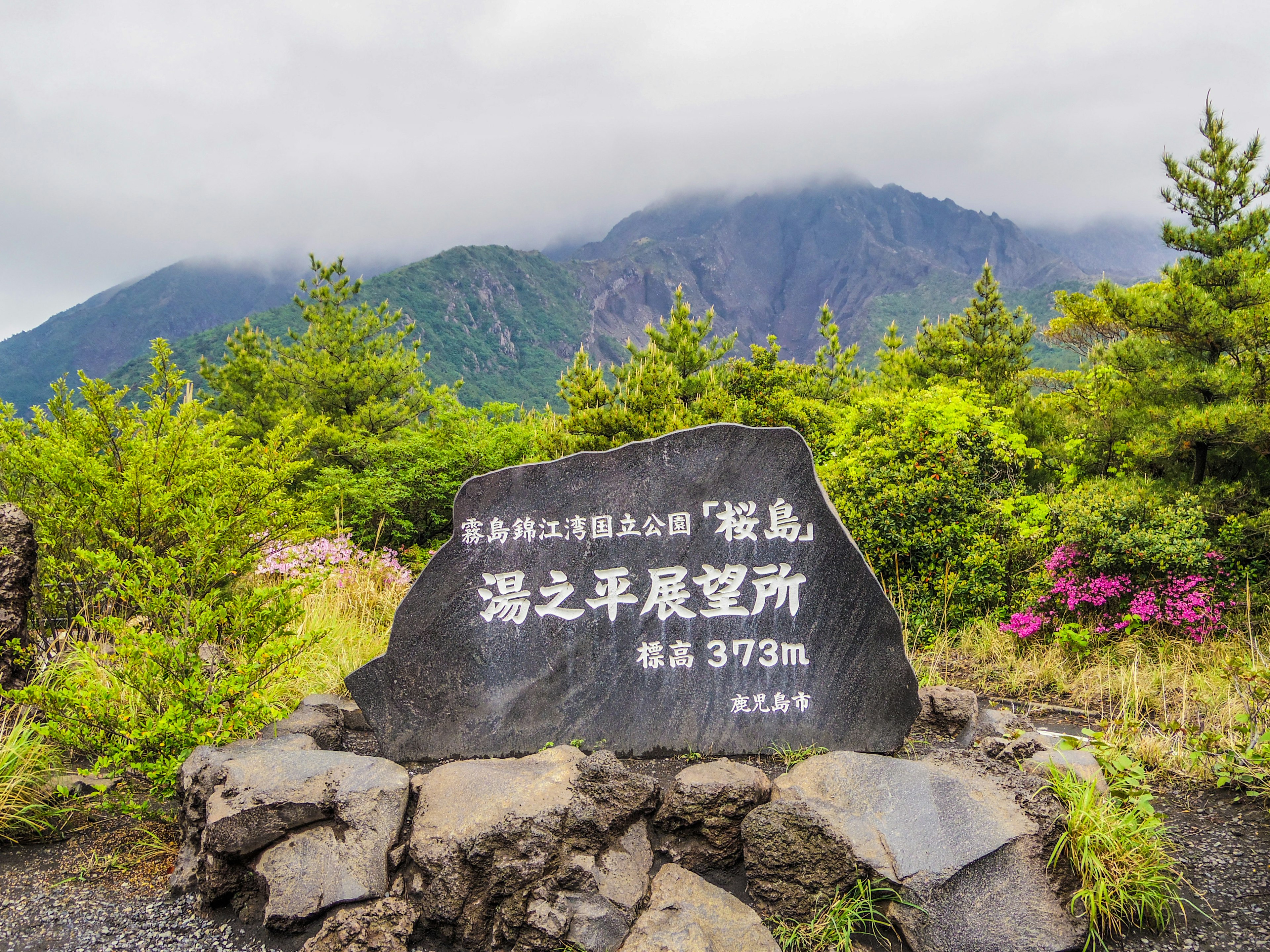 緑豊かな風景と山々を背景にした記念碑の画像