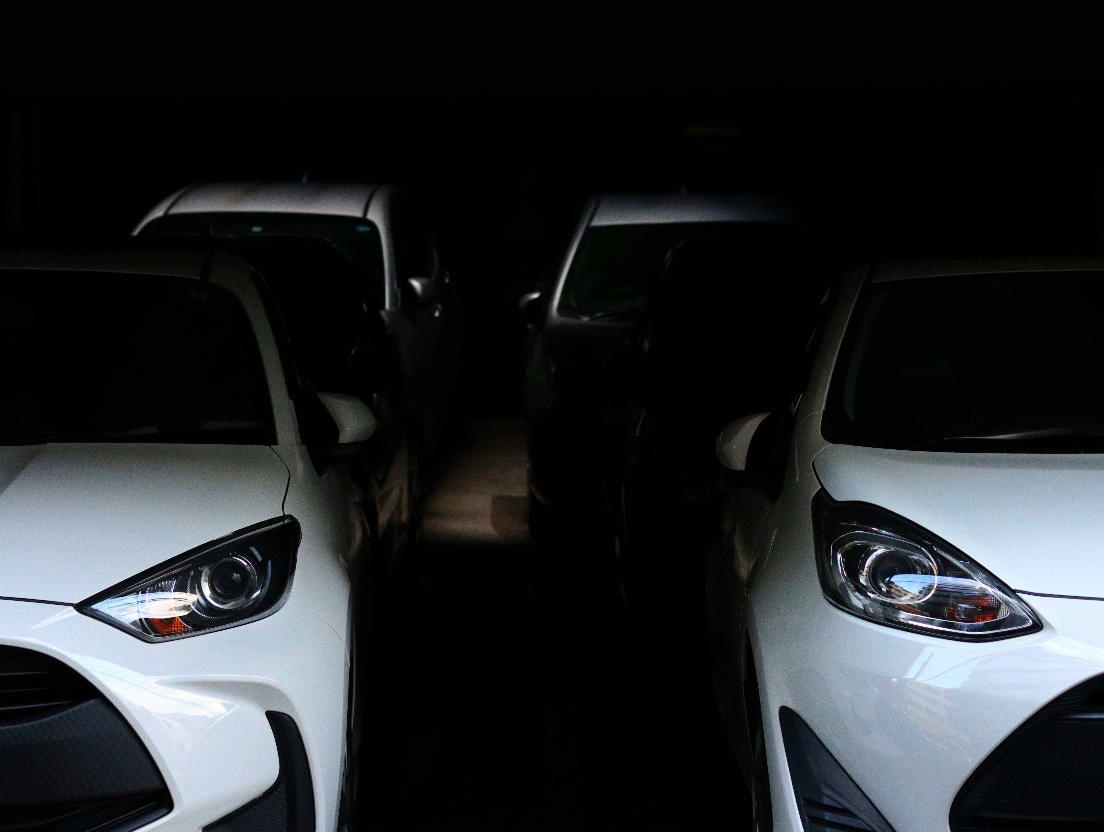 Close-up of white cars lined up in a dark setting