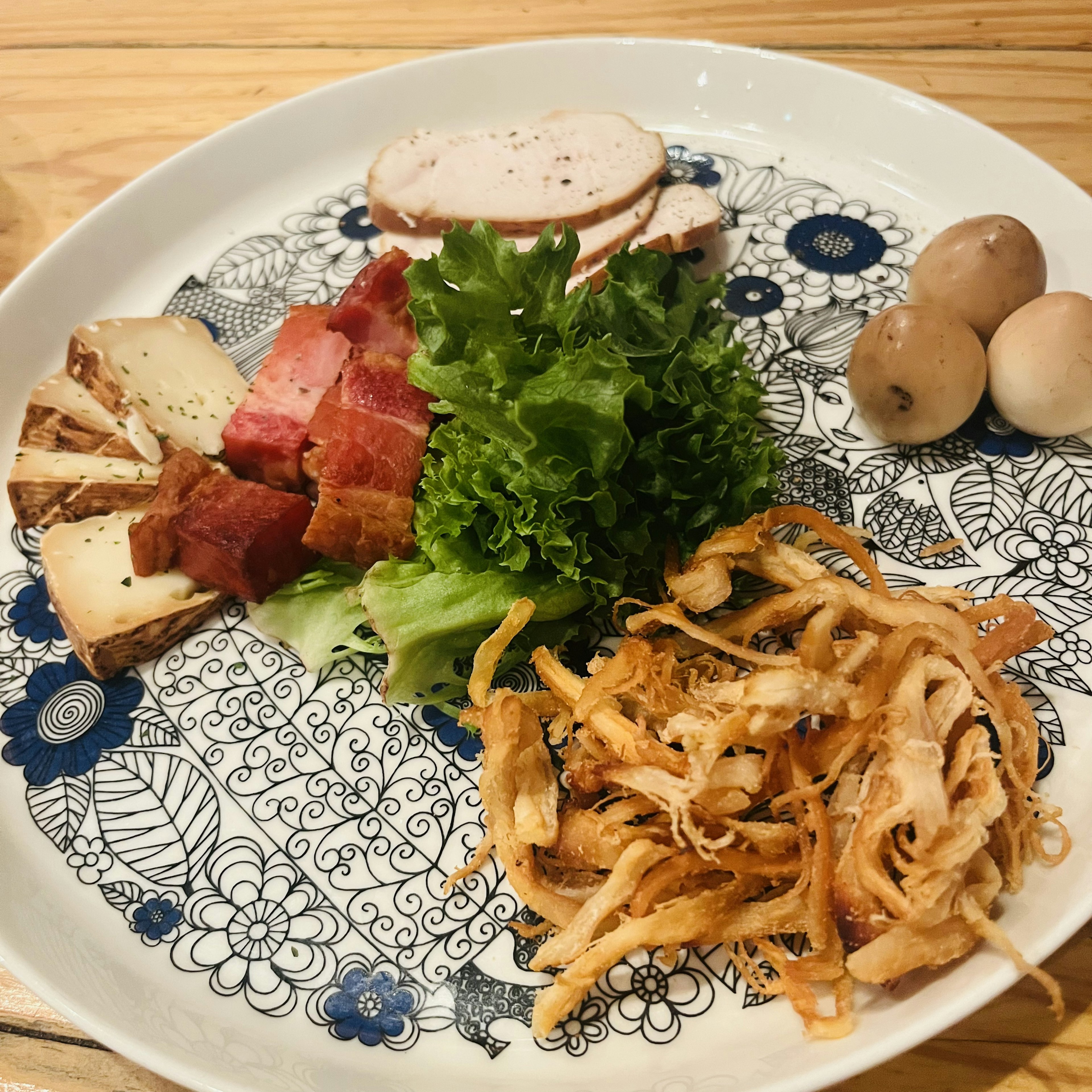 A plate featuring a variety of ingredients including ham, cheese, lettuce, shredded chicken, and boiled eggs