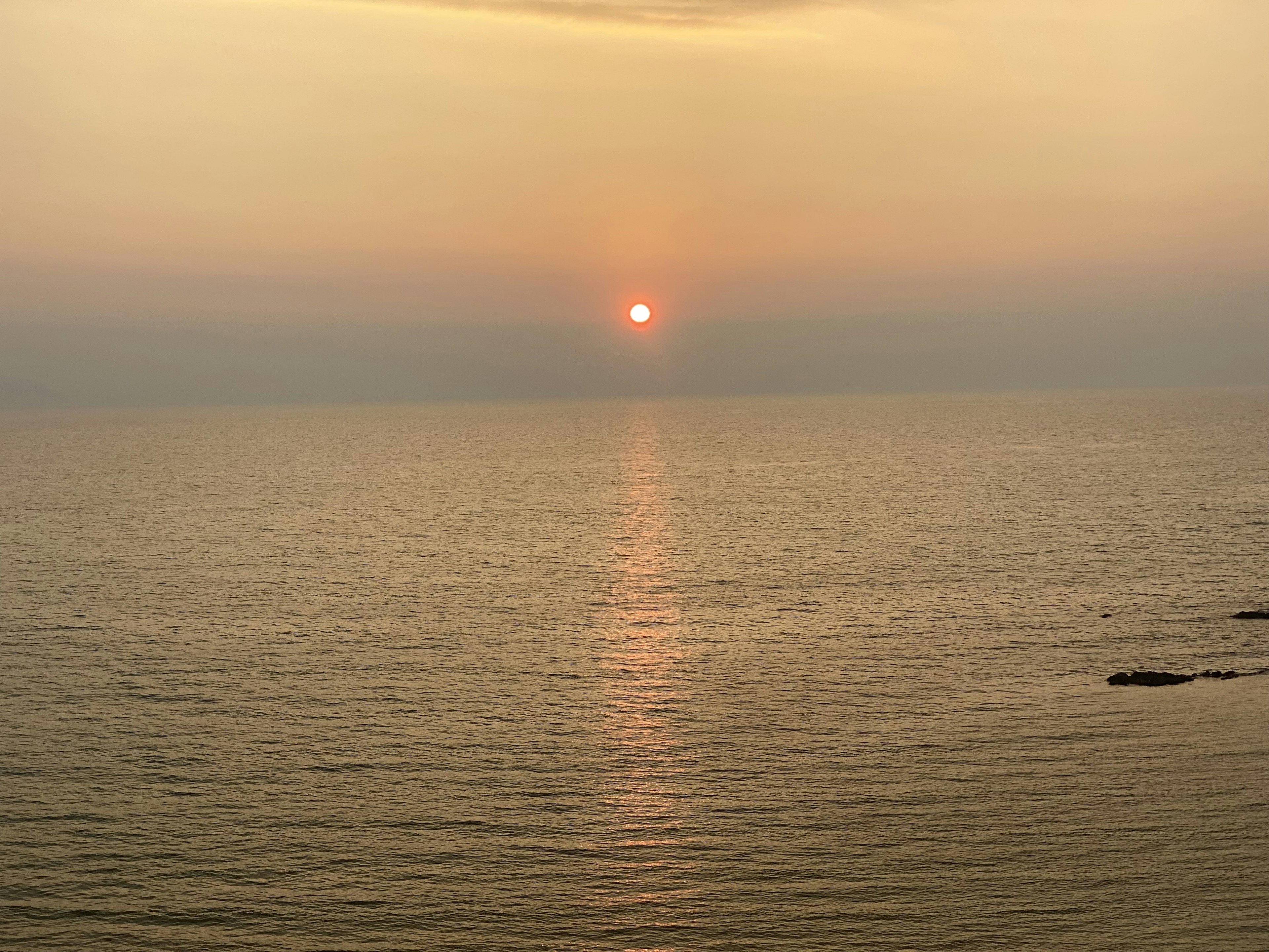 Sunset over the ocean with calm water reflections