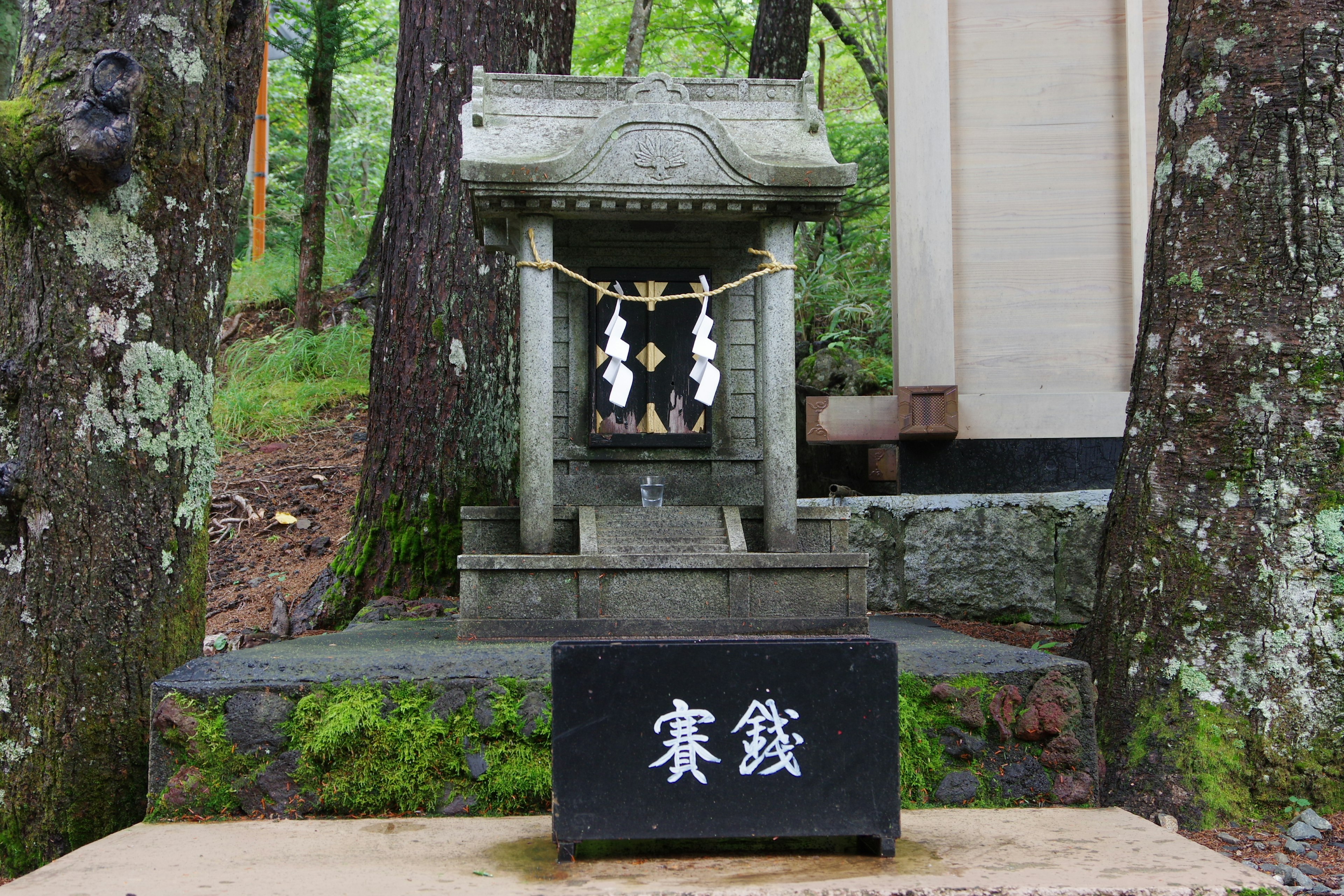 Small stone shrine surrounded by trees in a serene setting