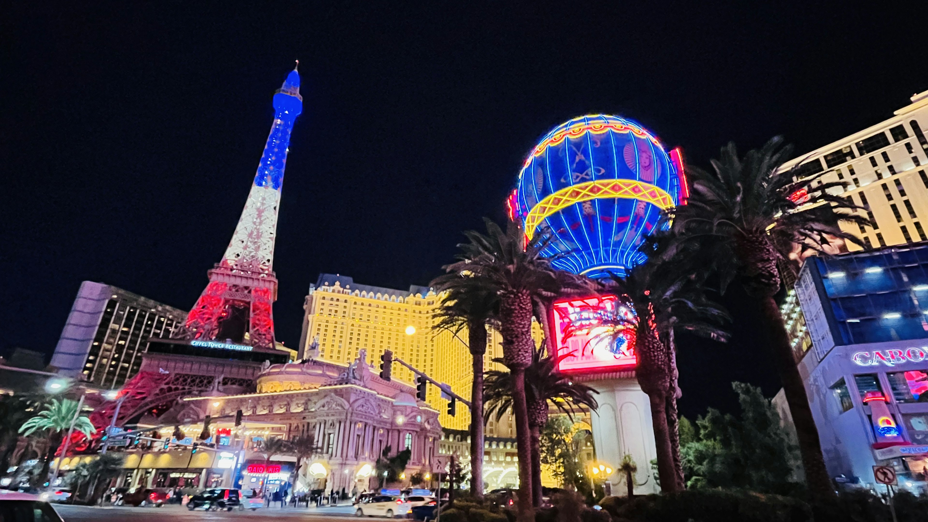 Vista notturna di Las Vegas con la Torre Eiffel e l'hotel Paris luci al neon colorate e palme