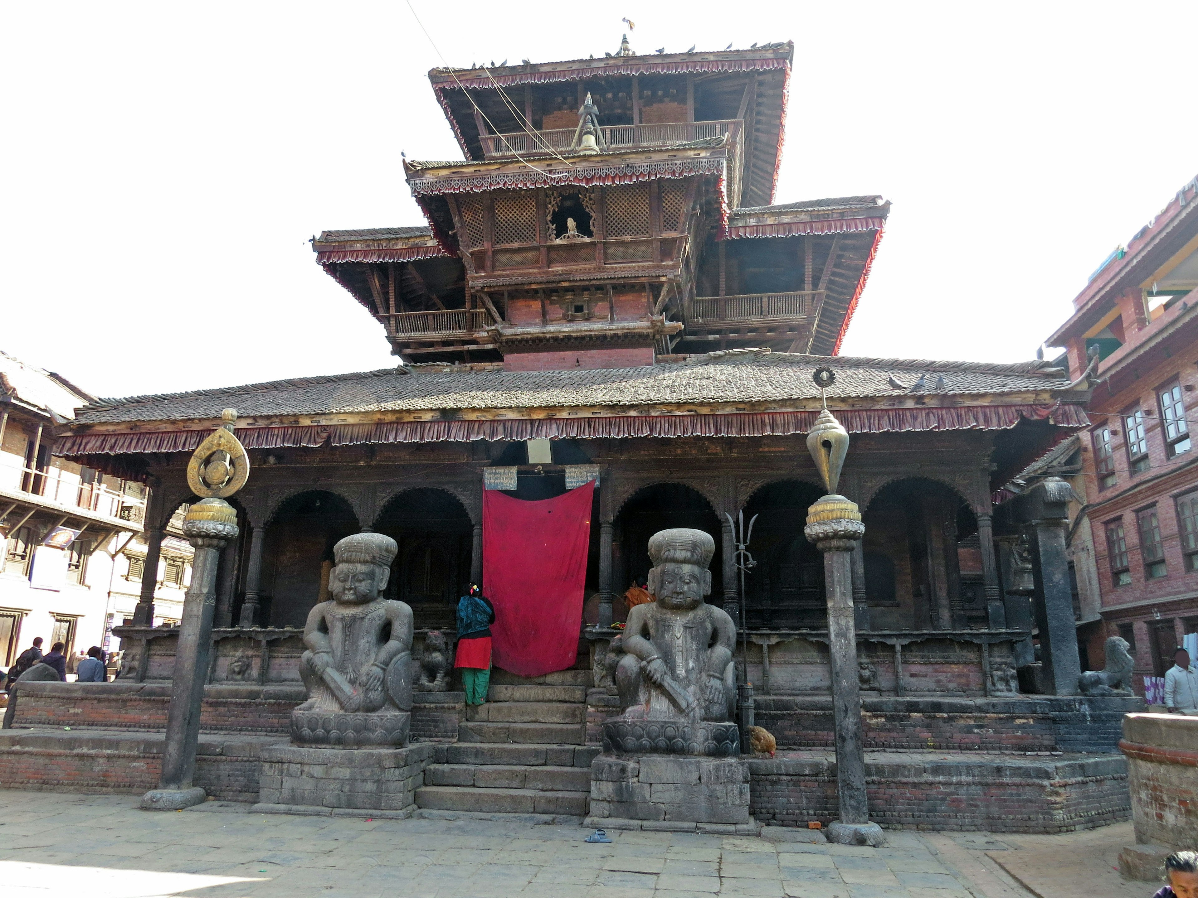 Exterior de un templo nepalés tradicional con un techo alto y estatuas de piedra talladas