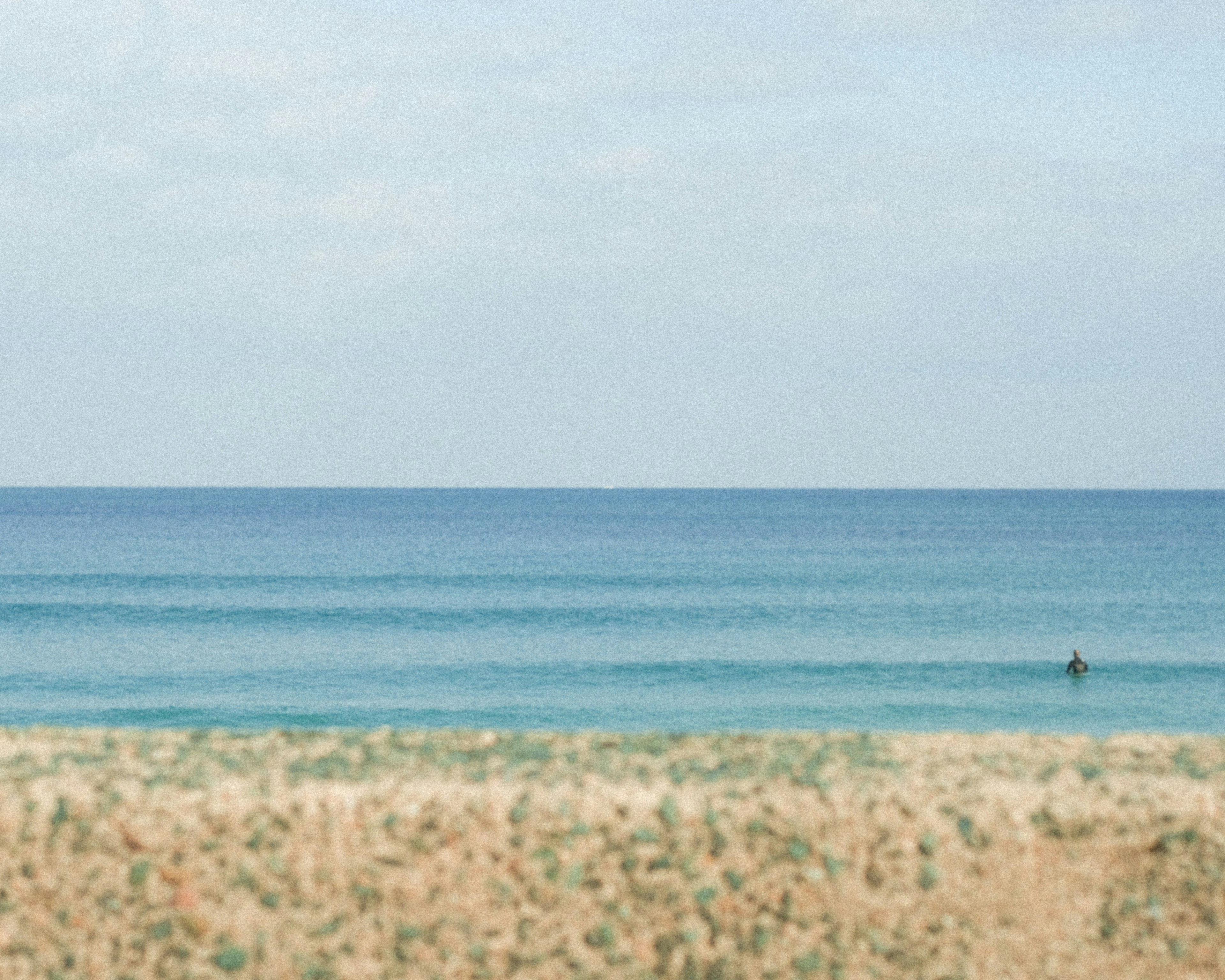 ทิวทัศน์ชายหาดสงบพร้อมมหาสมุทรสีน้ำเงินและชายฝั่งทราย