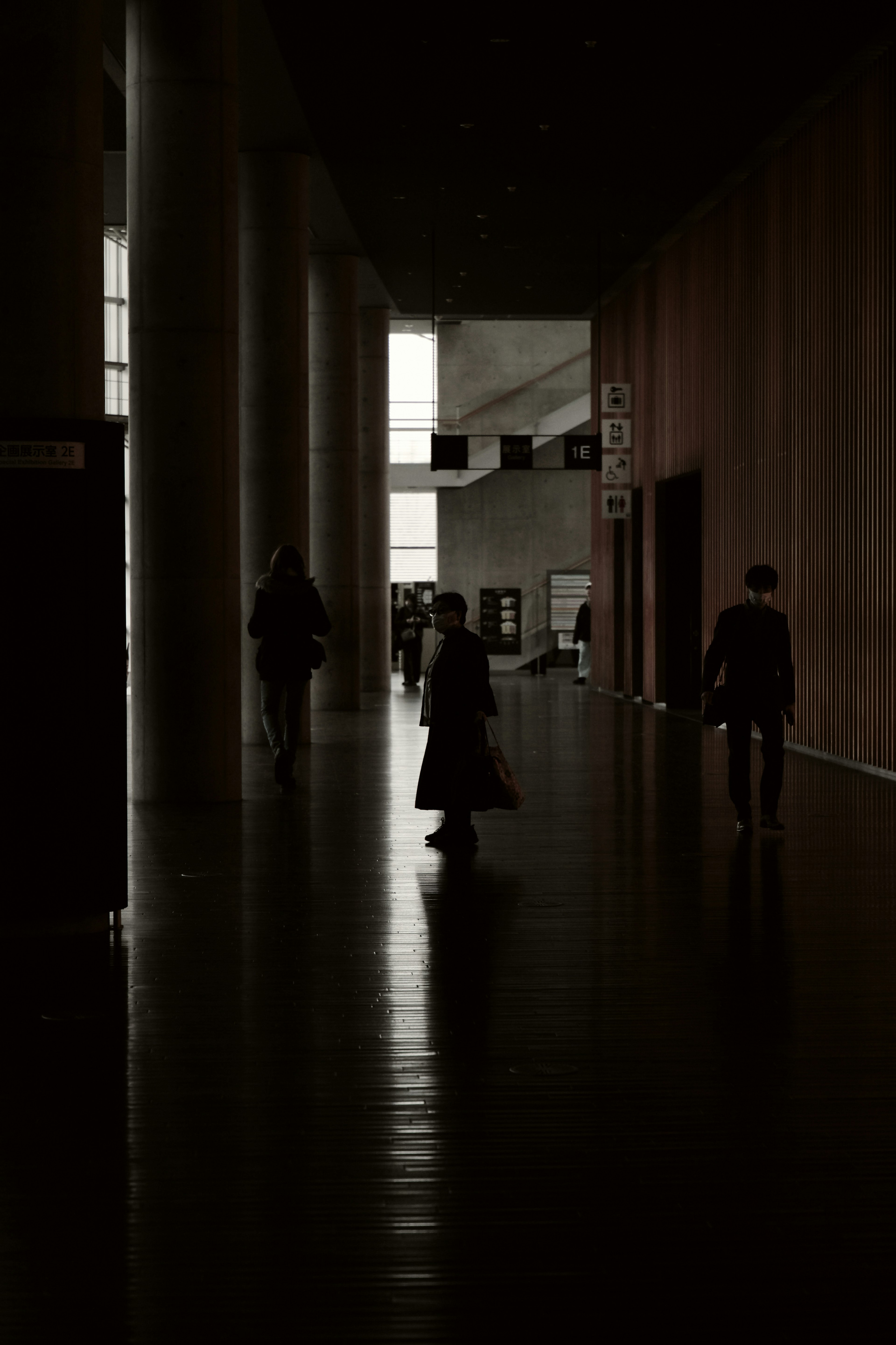 Silhouettes de personnes marchant dans un couloir sombre