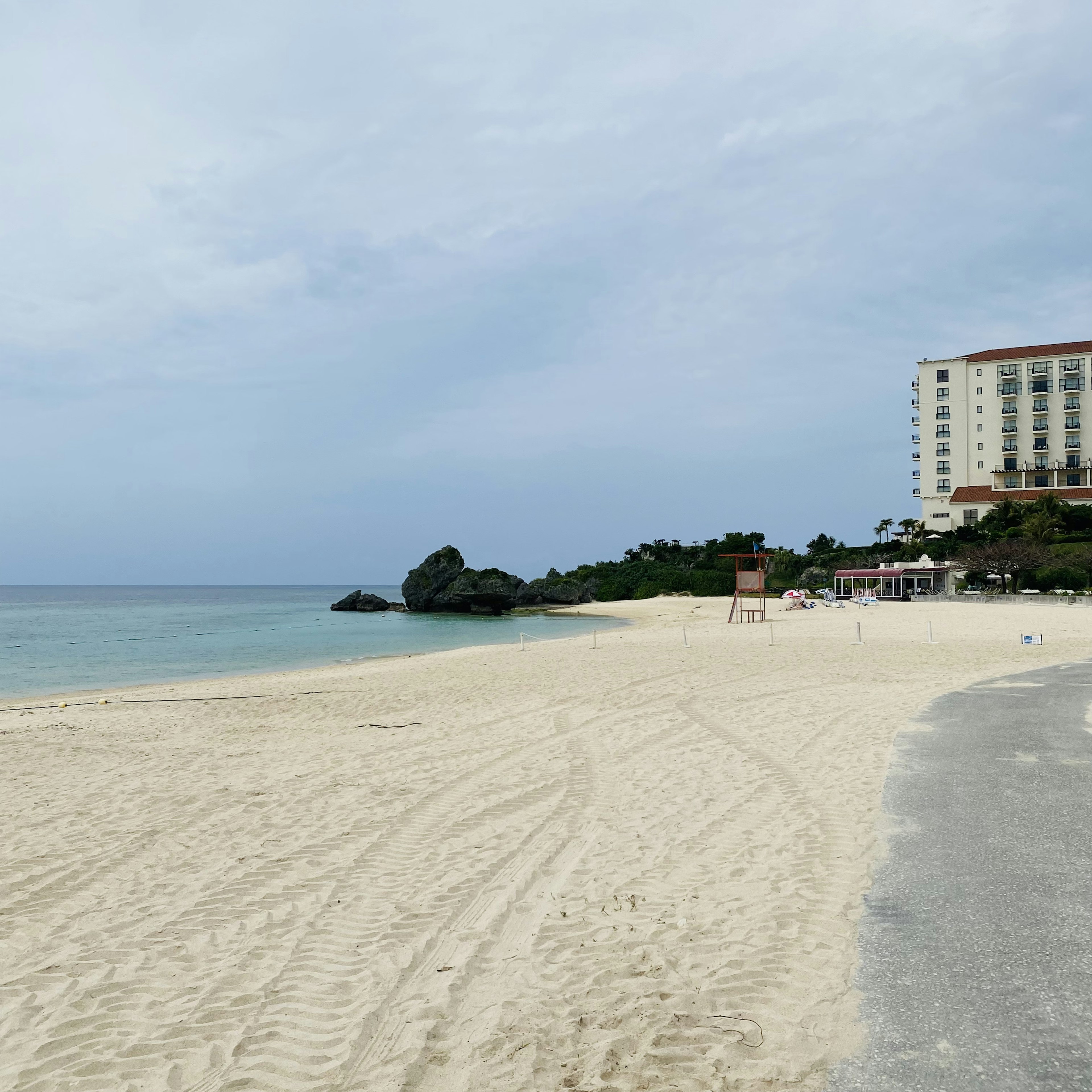 Scenic beach view with white sand and blue ocean High-rise hotel in the background