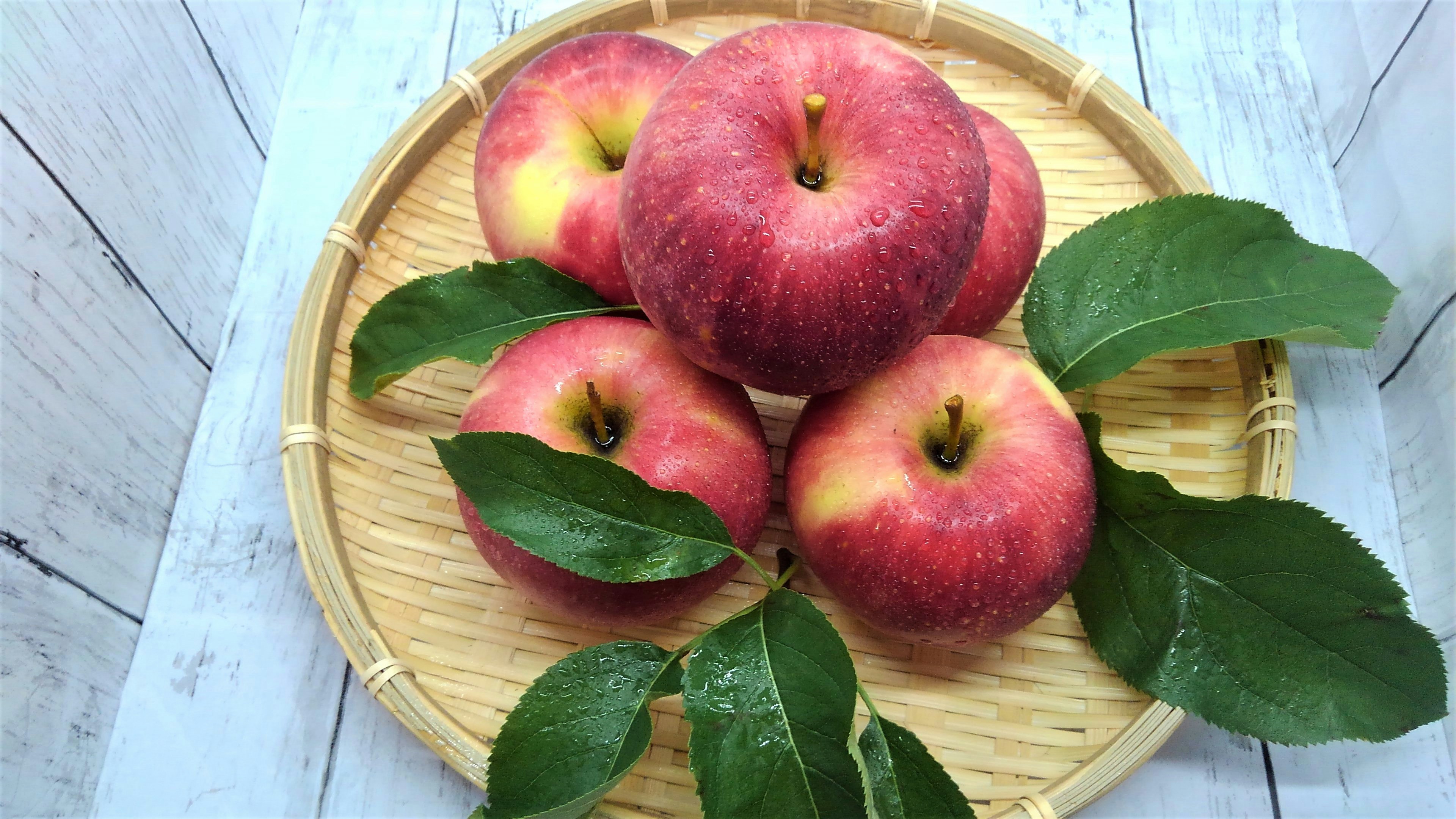 Red apples arranged with leaves on a bamboo tray