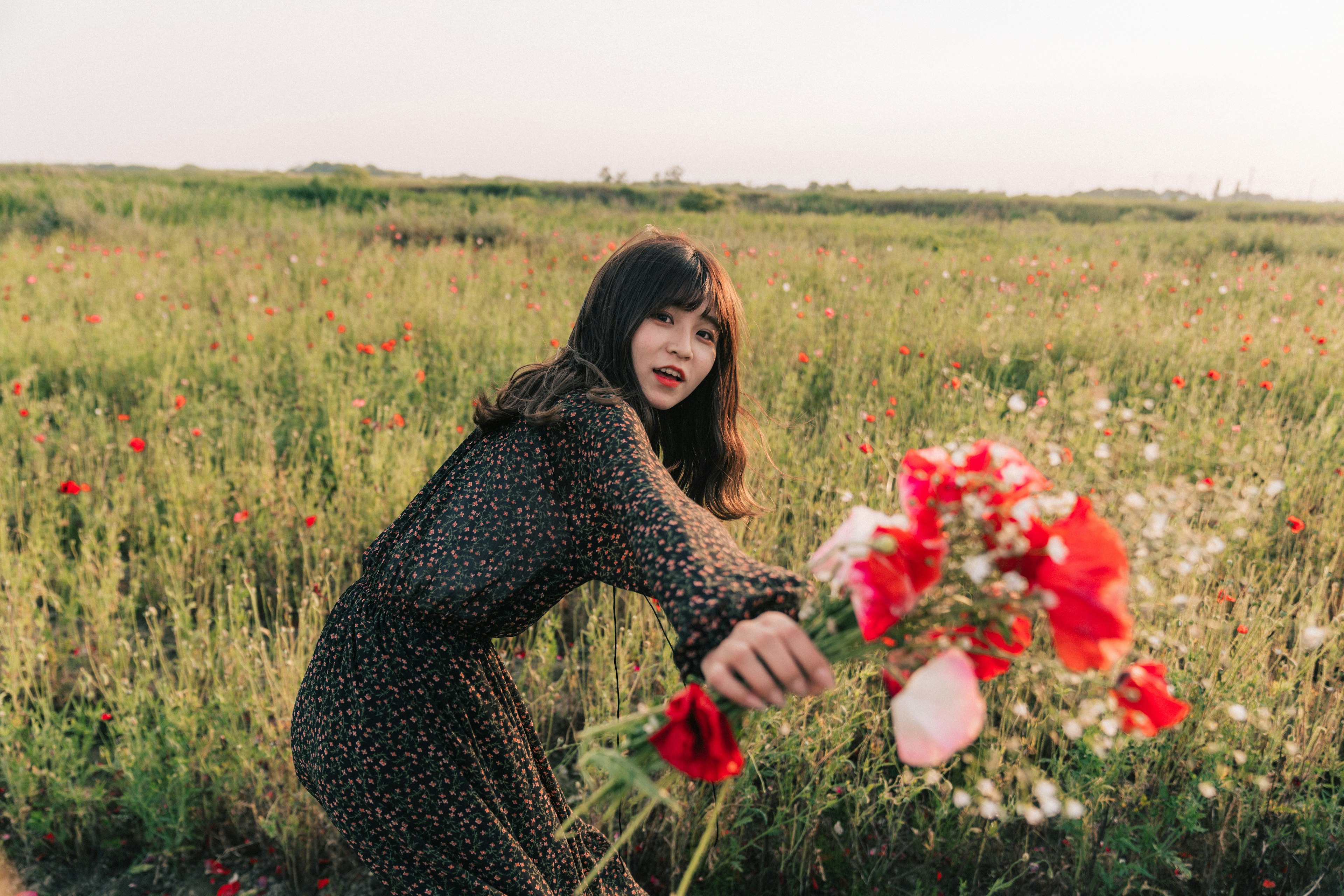 草原の中で花束を持つ女性の後ろ姿