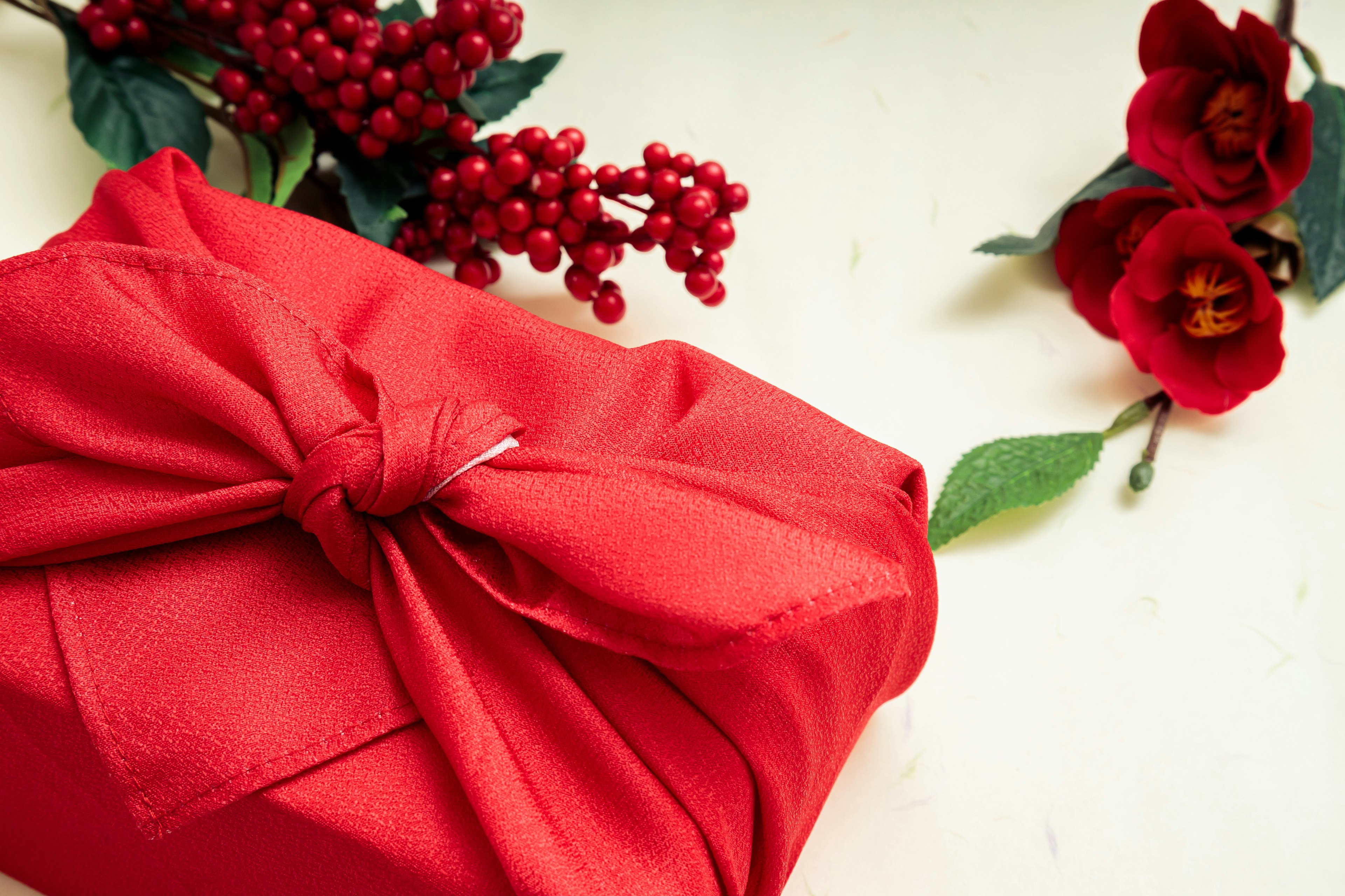 A red fabric-wrapped gift with decorative red flowers