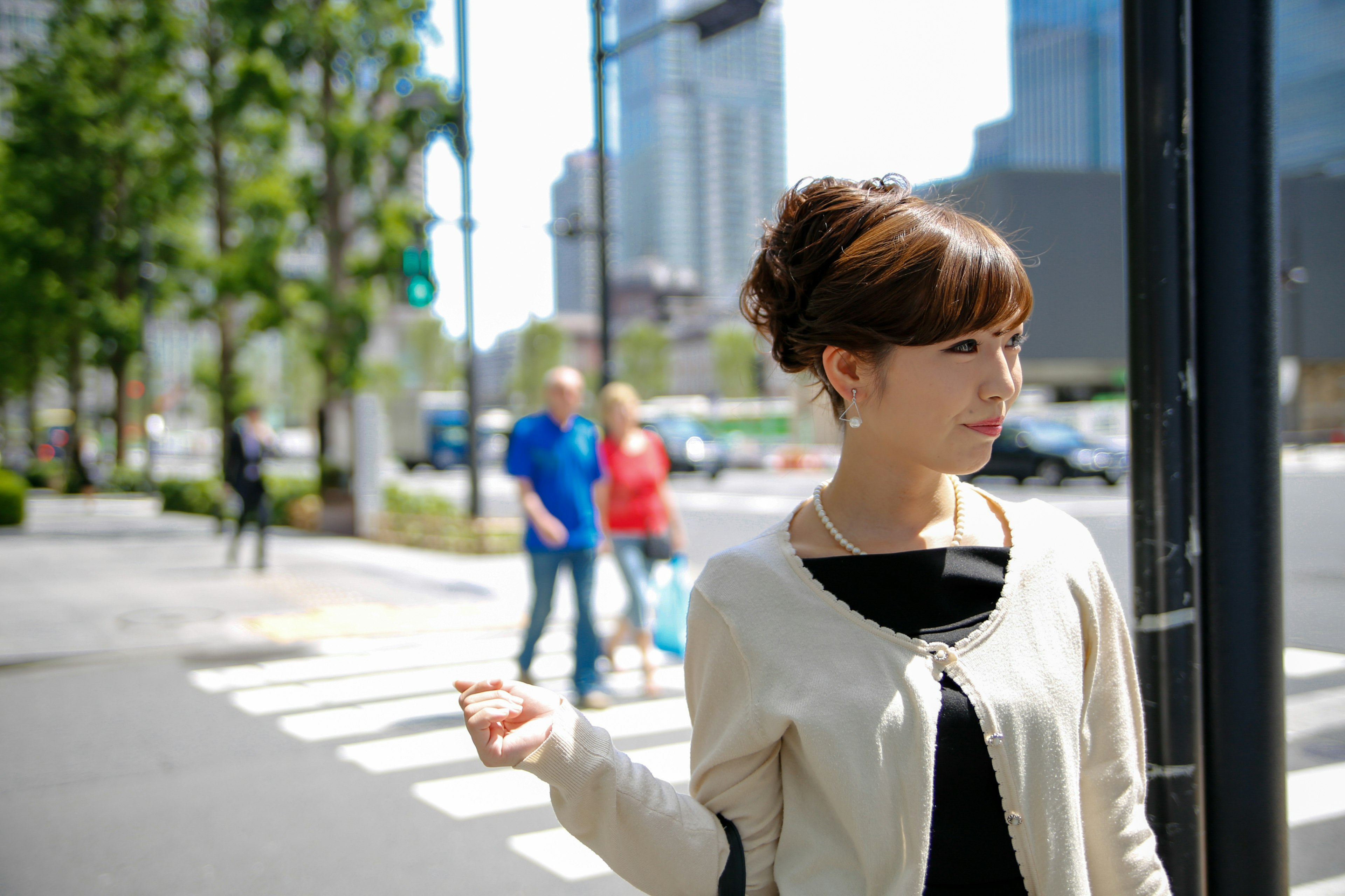 Mujer esperando en un semáforo en la ciudad cielo azul claro y rascacielos de fondo