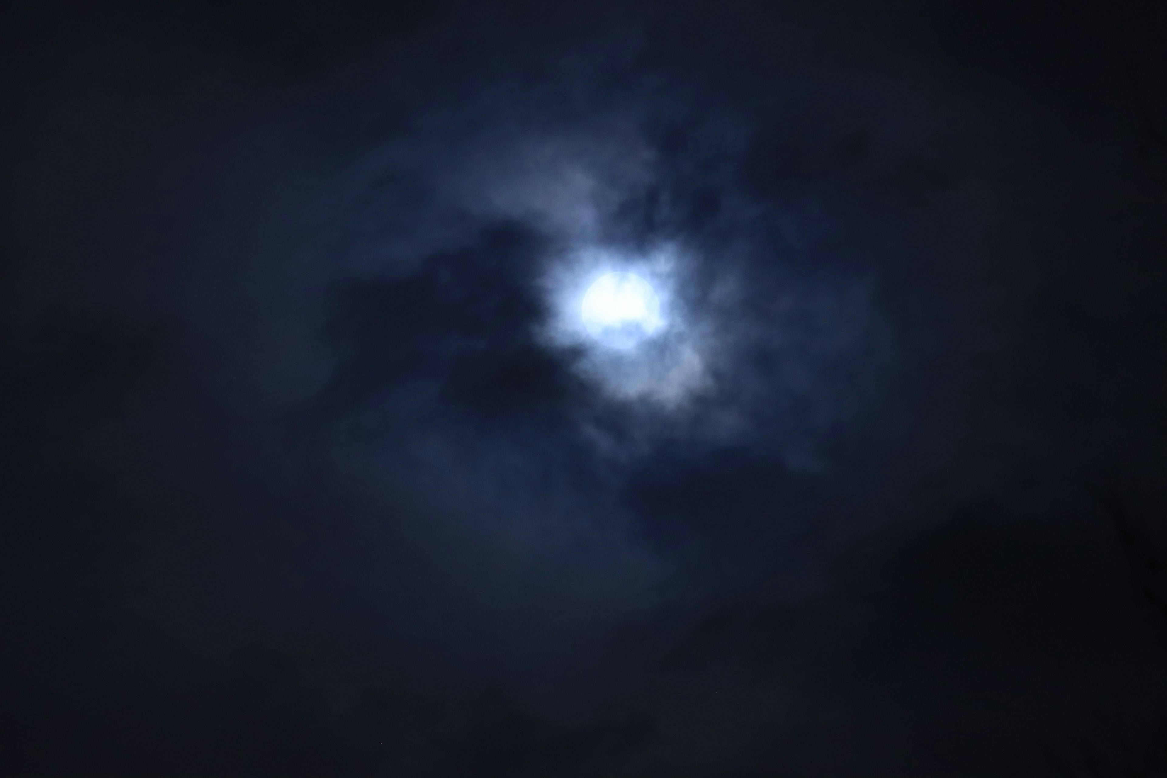 Bright moon partially obscured by dark clouds