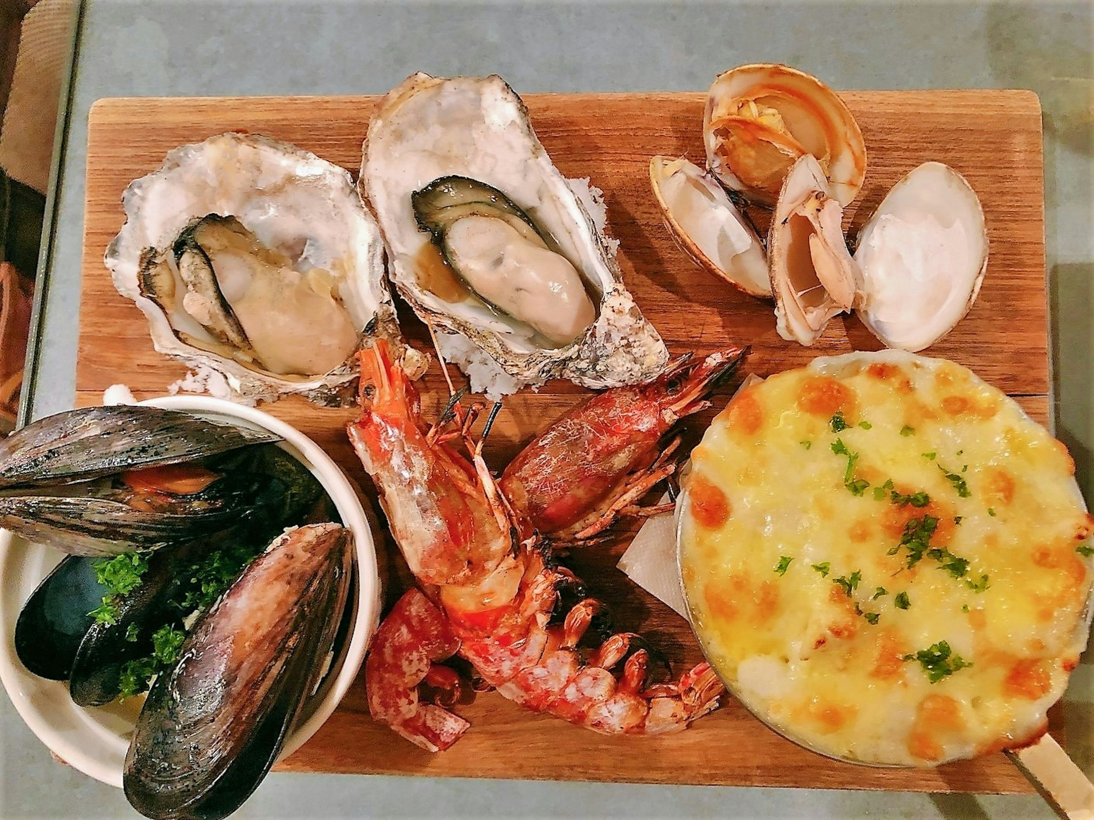 A fresh seafood platter featuring oysters mussels shrimp scallops and a creamy gratin