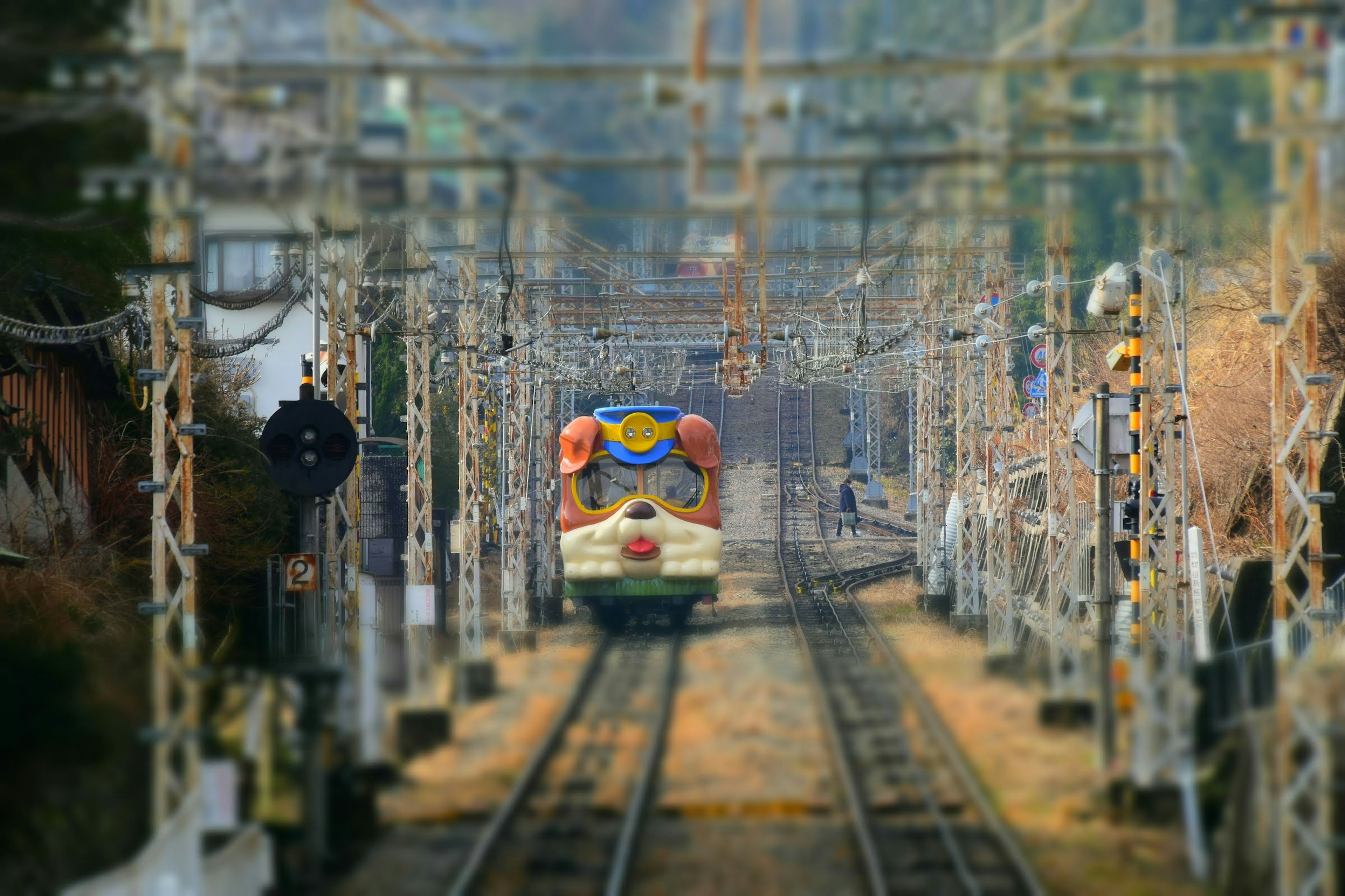 線路を走るカラフルな列車と周囲の架線が特徴的な風景