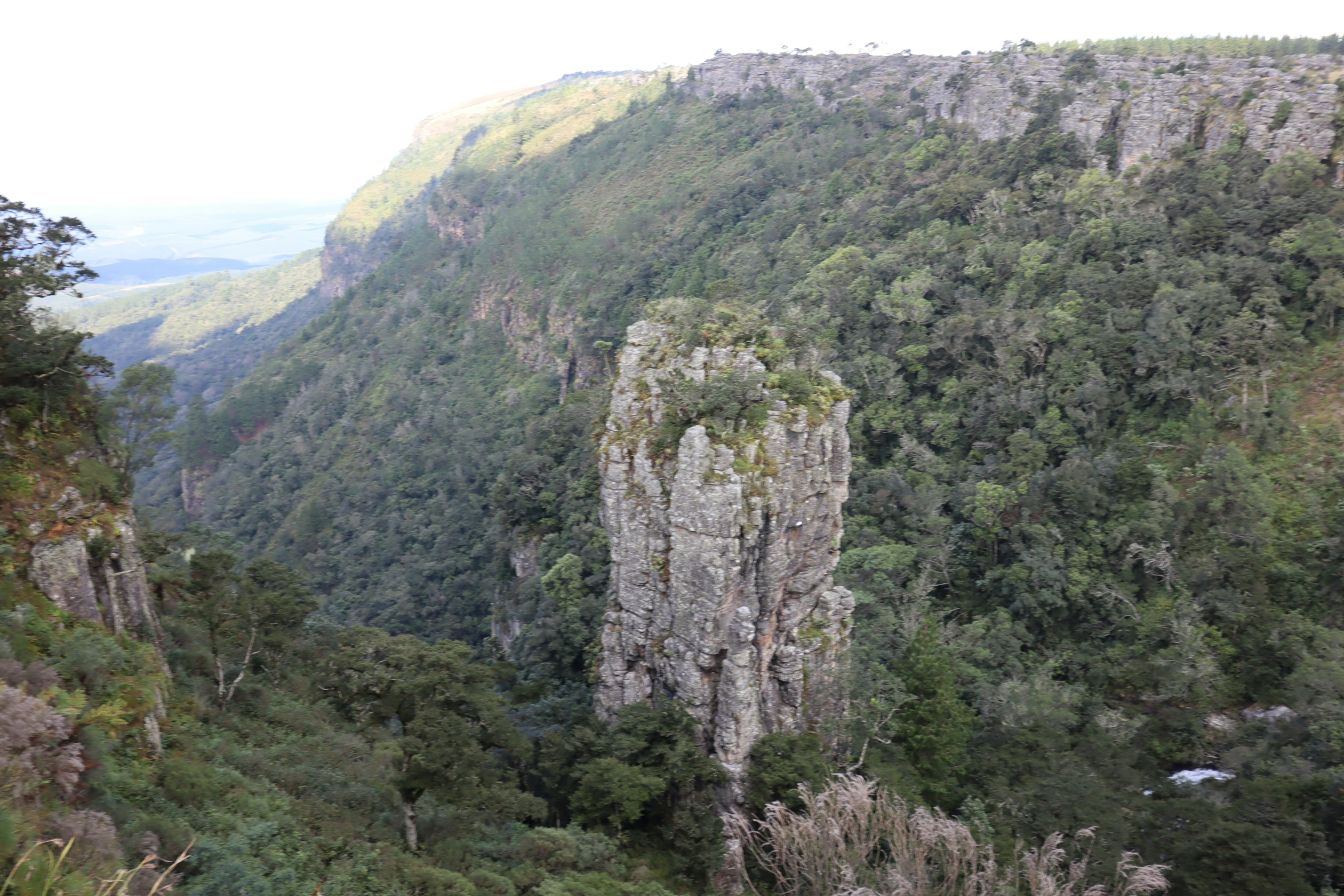 A large rock pillar rising among lush green mountains