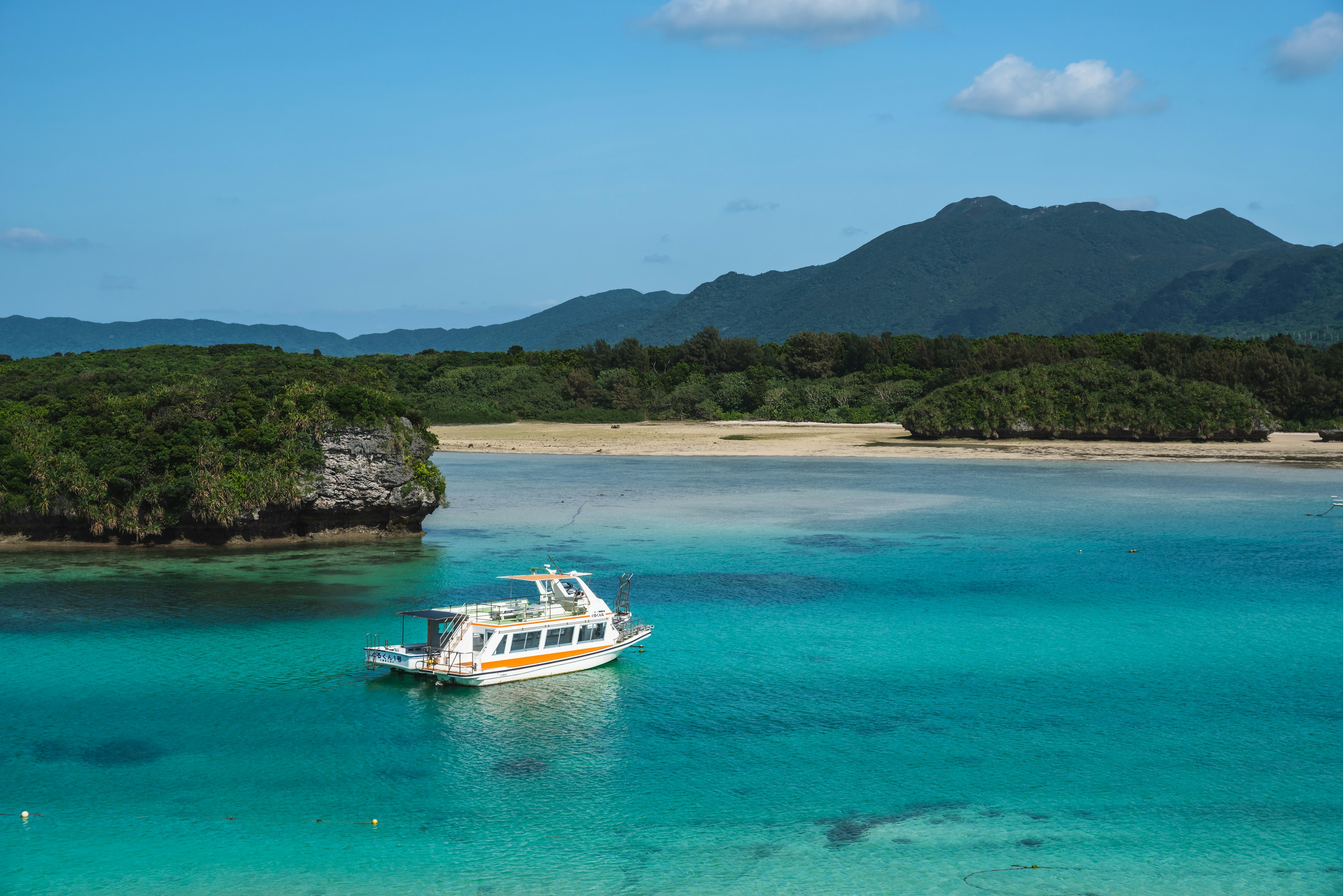 Bateau ancré dans des eaux turquoise claires près d'une île verdoyante