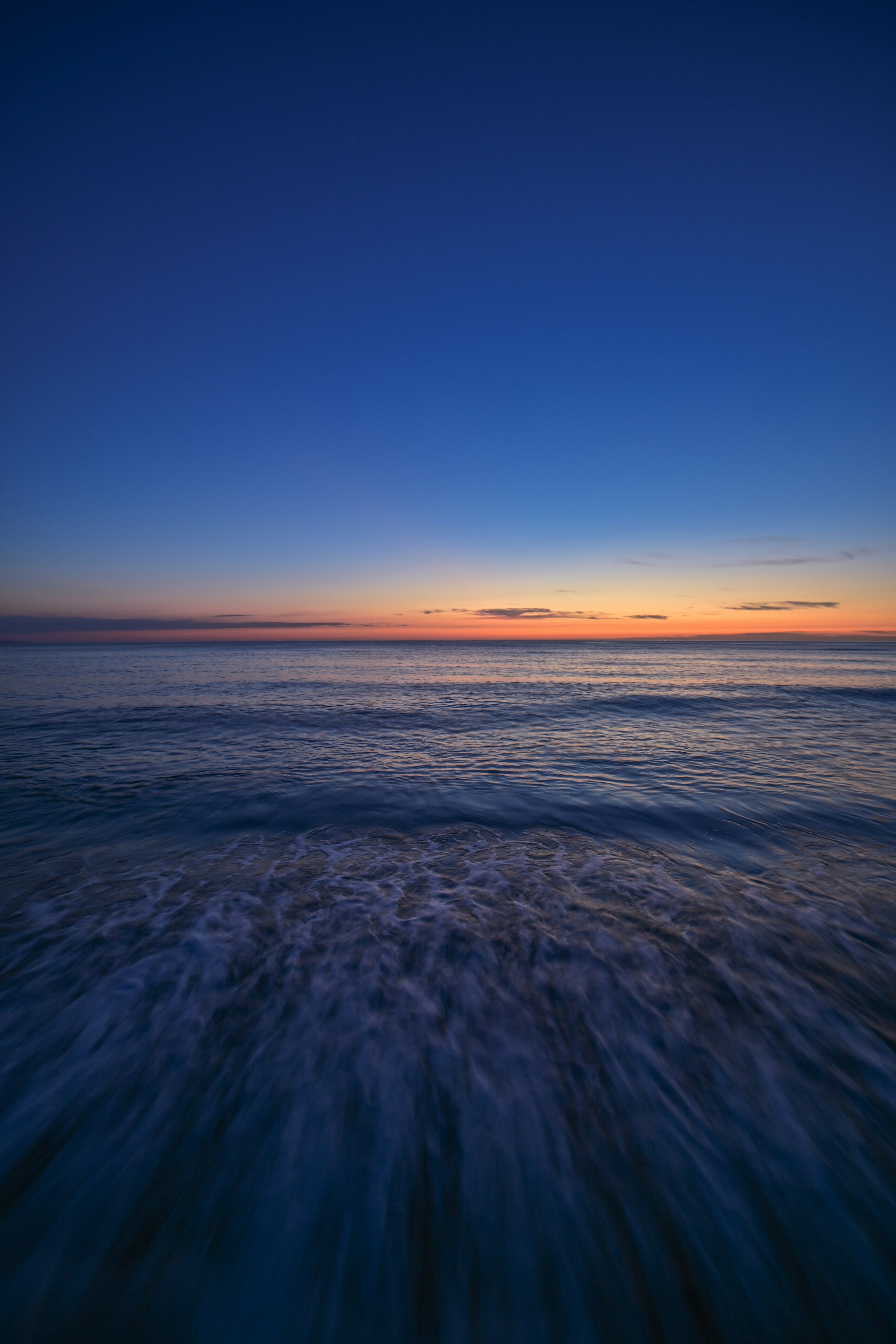 Una vista serena dell'oceano al tramonto con una gradazione di blu e arancione