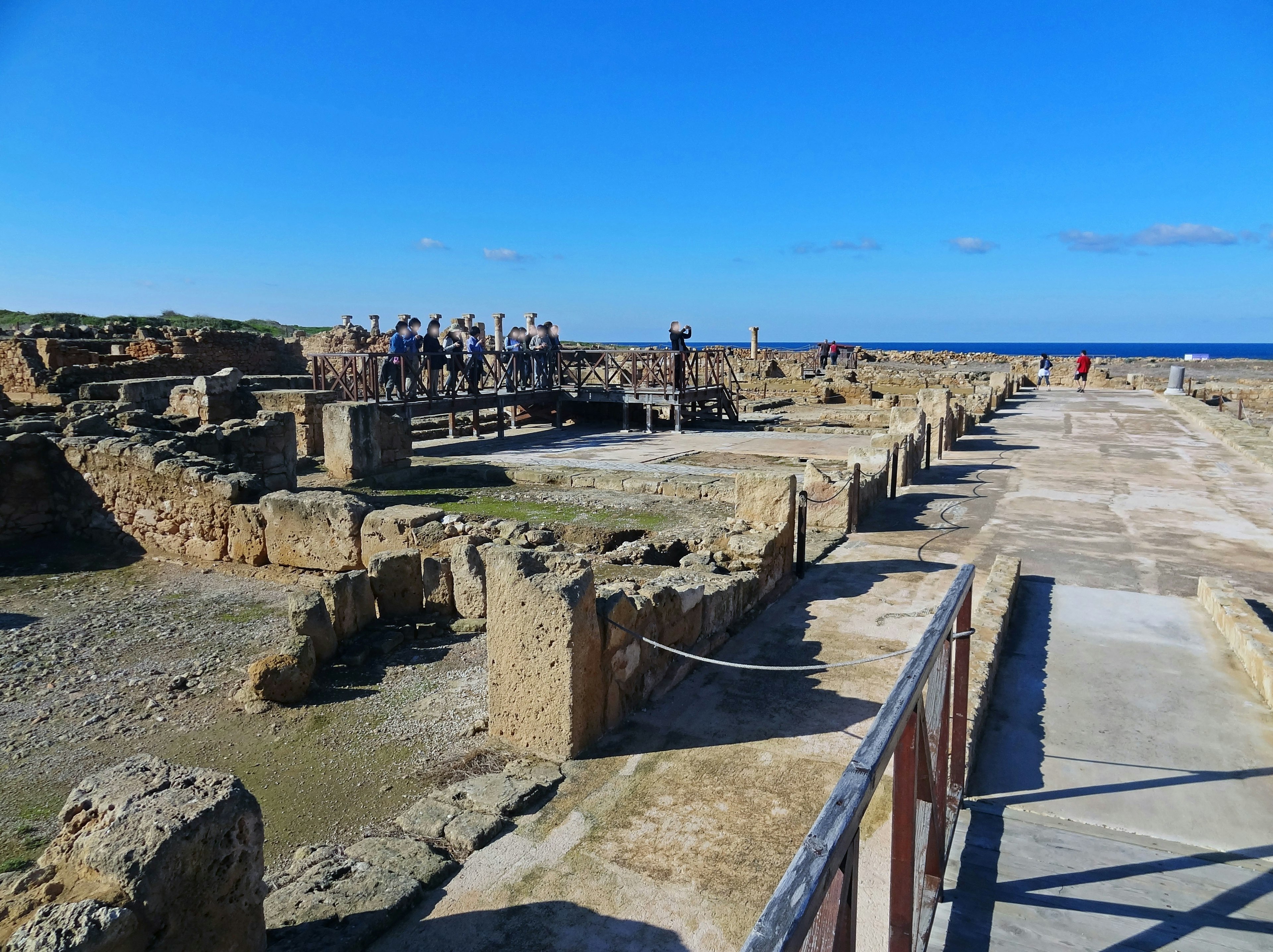 Vista delle rovine antiche con turisti sotto un cielo blu