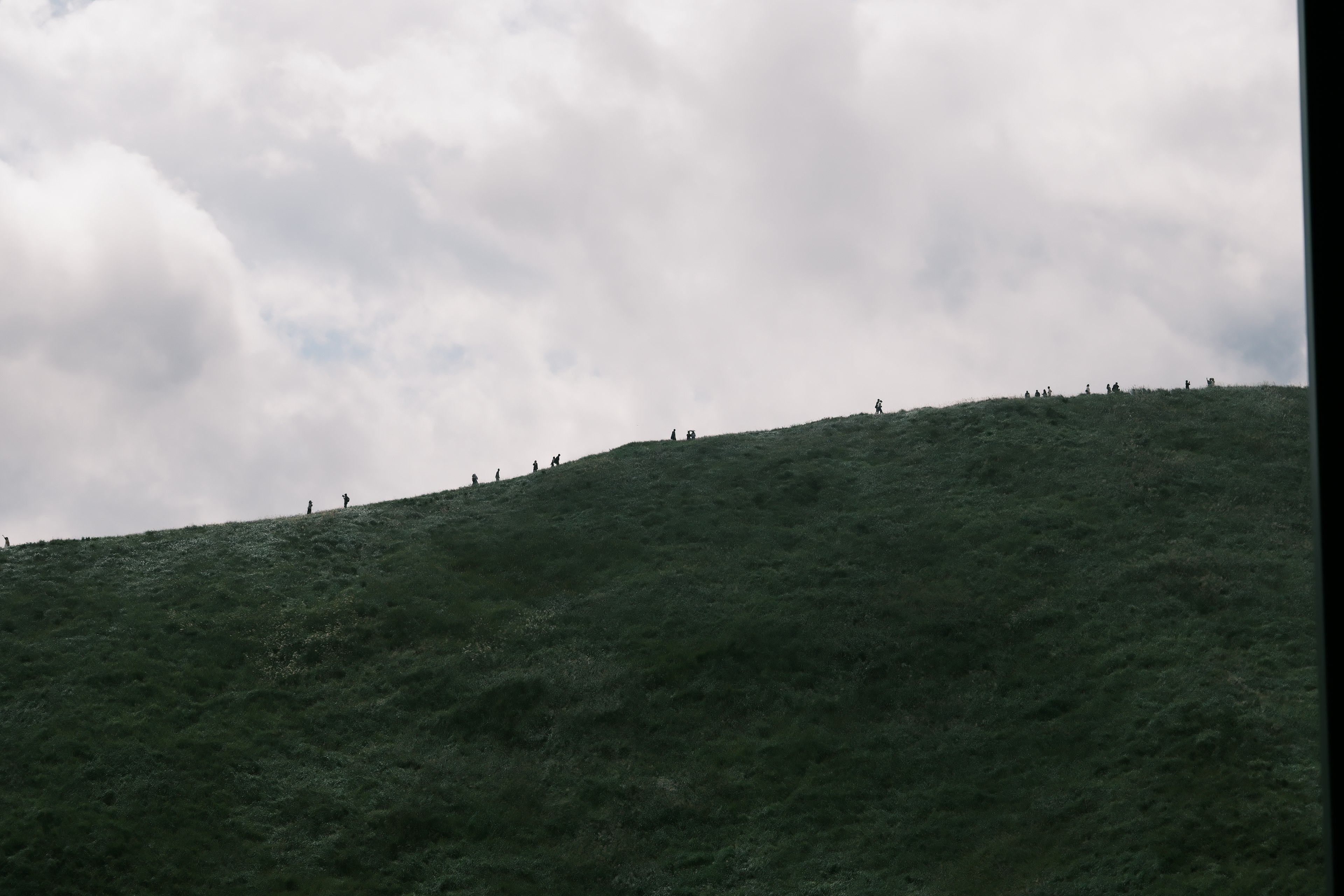 Paysage avec de petites silhouettes dispersées sur une colline verte