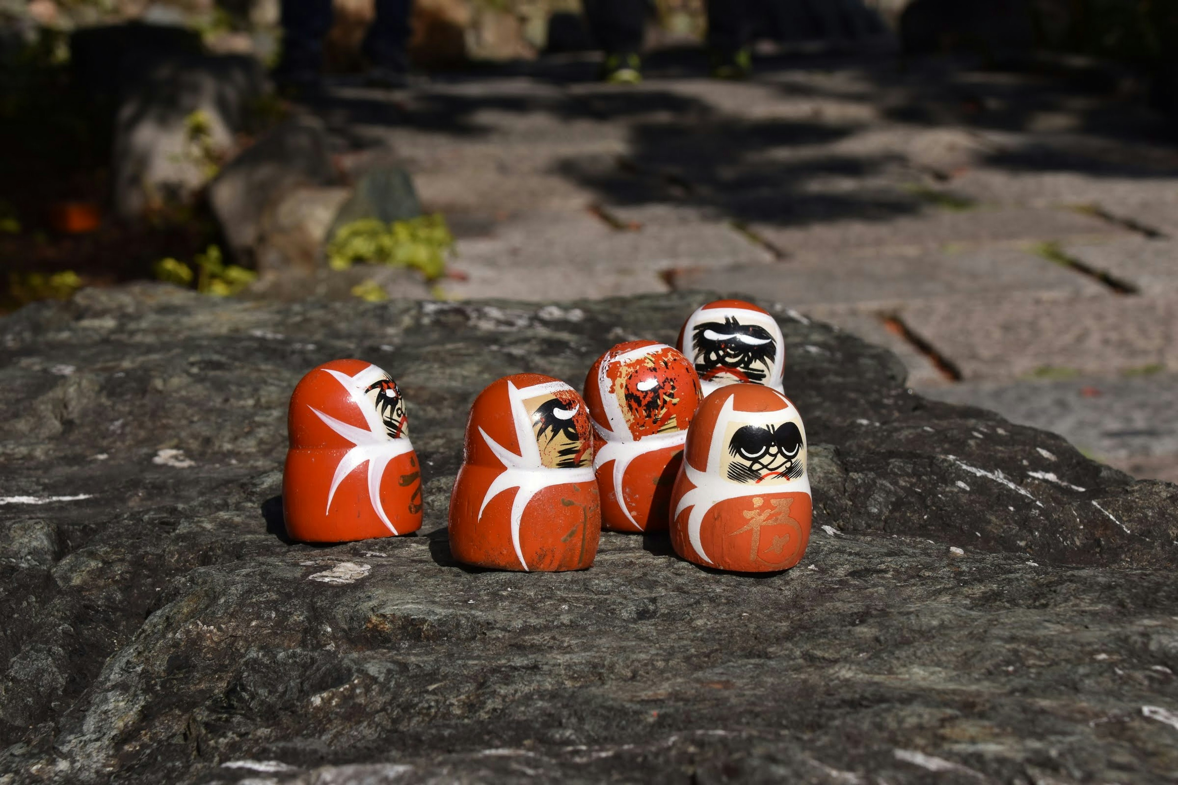 Eine Gruppe von Daruma-Puppen auf einem Felsen in einer natürlichen Umgebung