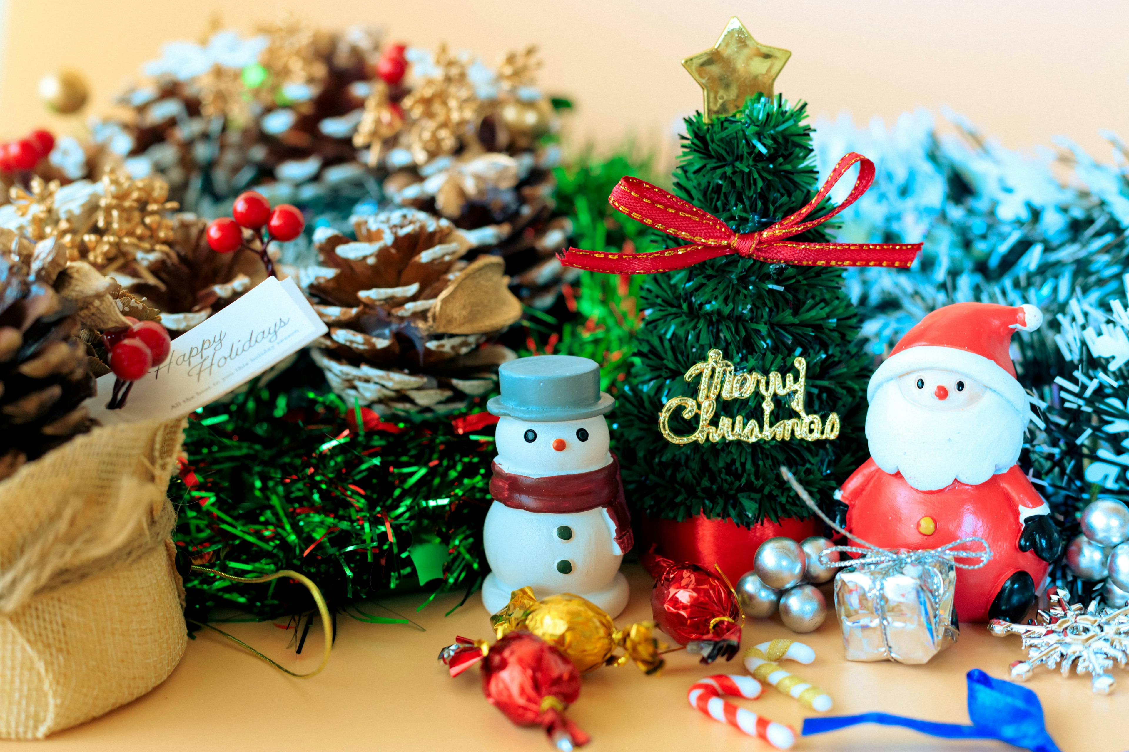 Eine festliche Weihnachtsszene mit einem kleinen geschmückten Baum einer Weihnachtsmannfigur und einem Schneemann umgeben von bunten Ornamenten und Tannenzapfen