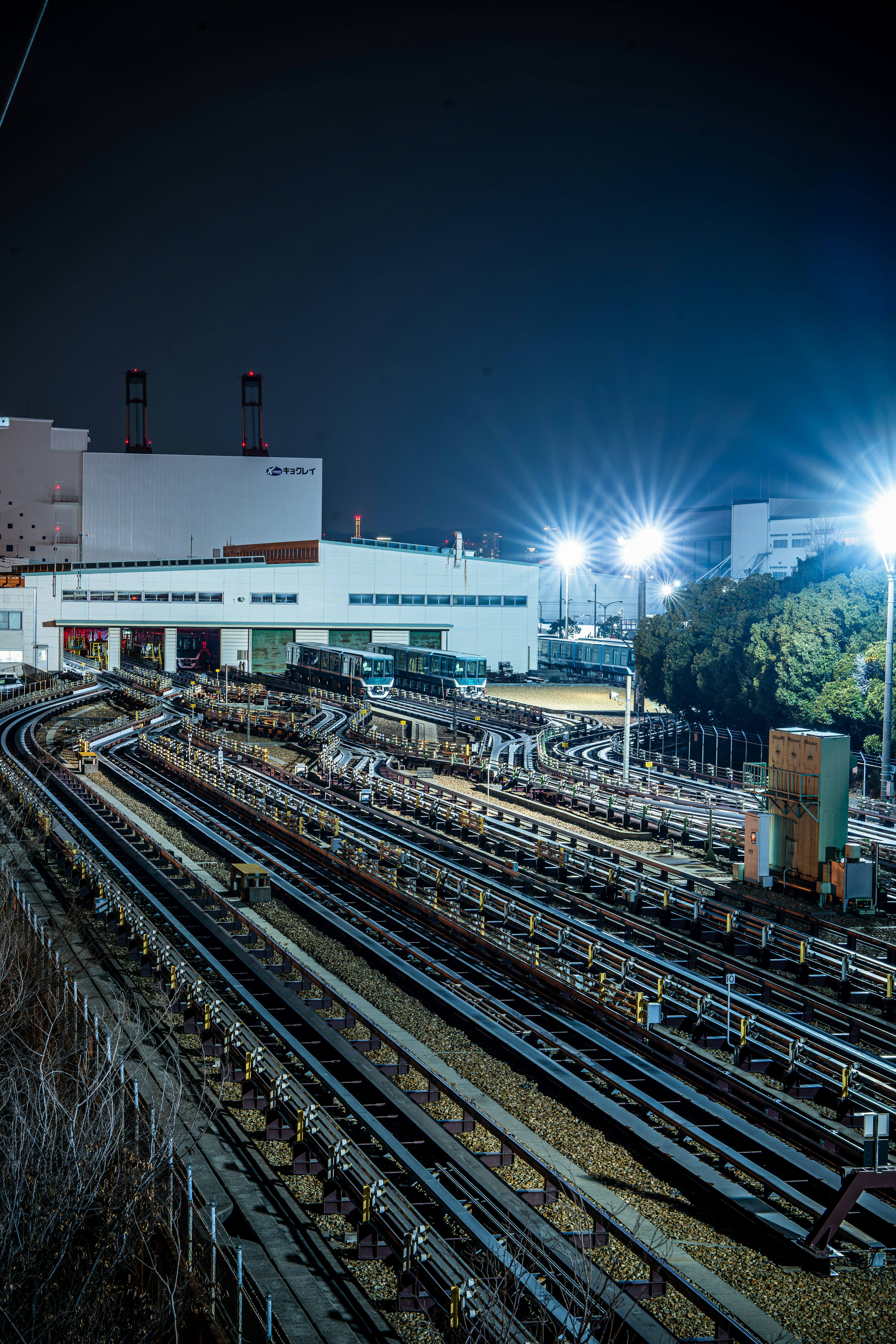 夜の鉄道トラックと工場の風景明るい街灯が照らす