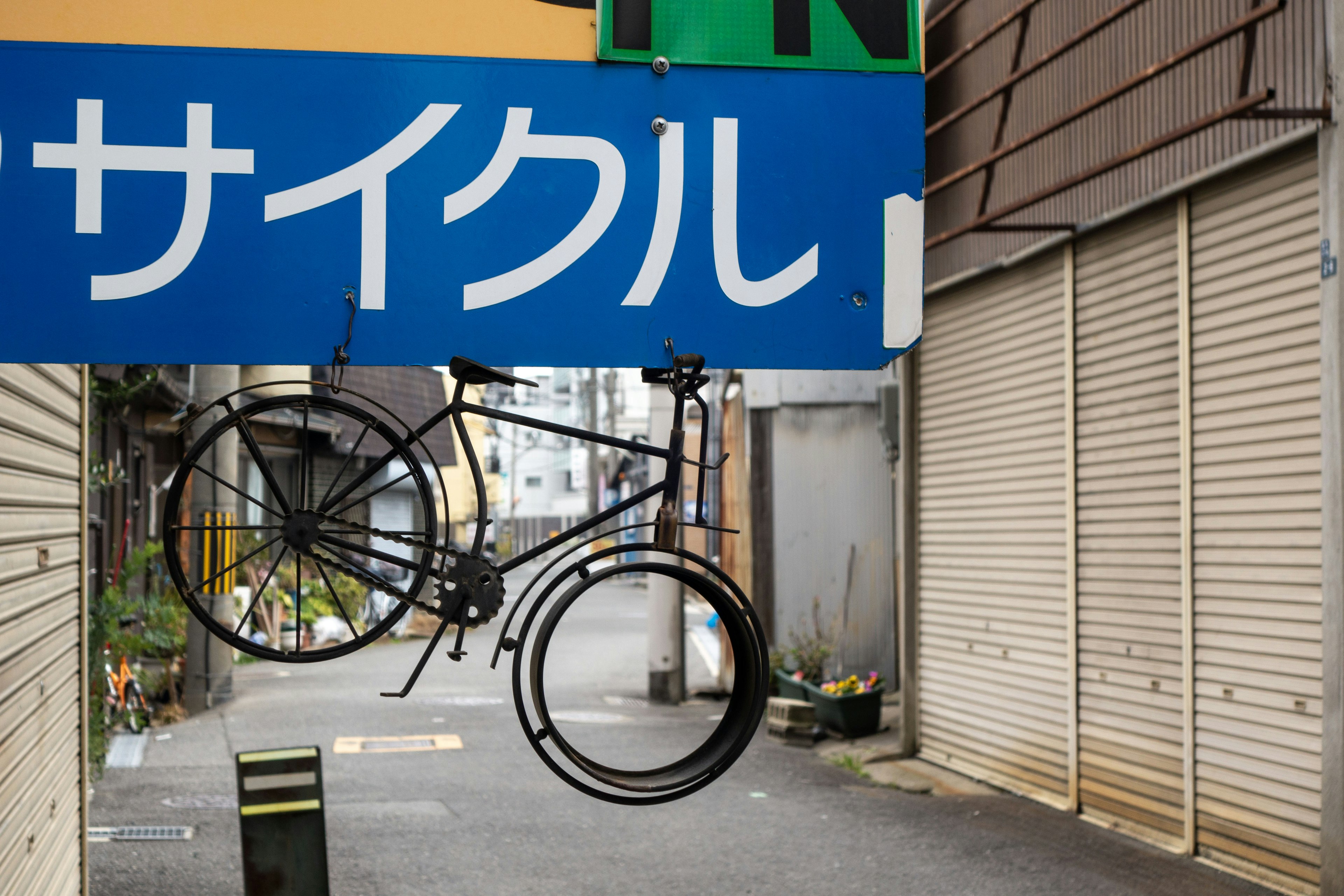 サイクルショップの看板にぶら下がる自転車のオブジェ