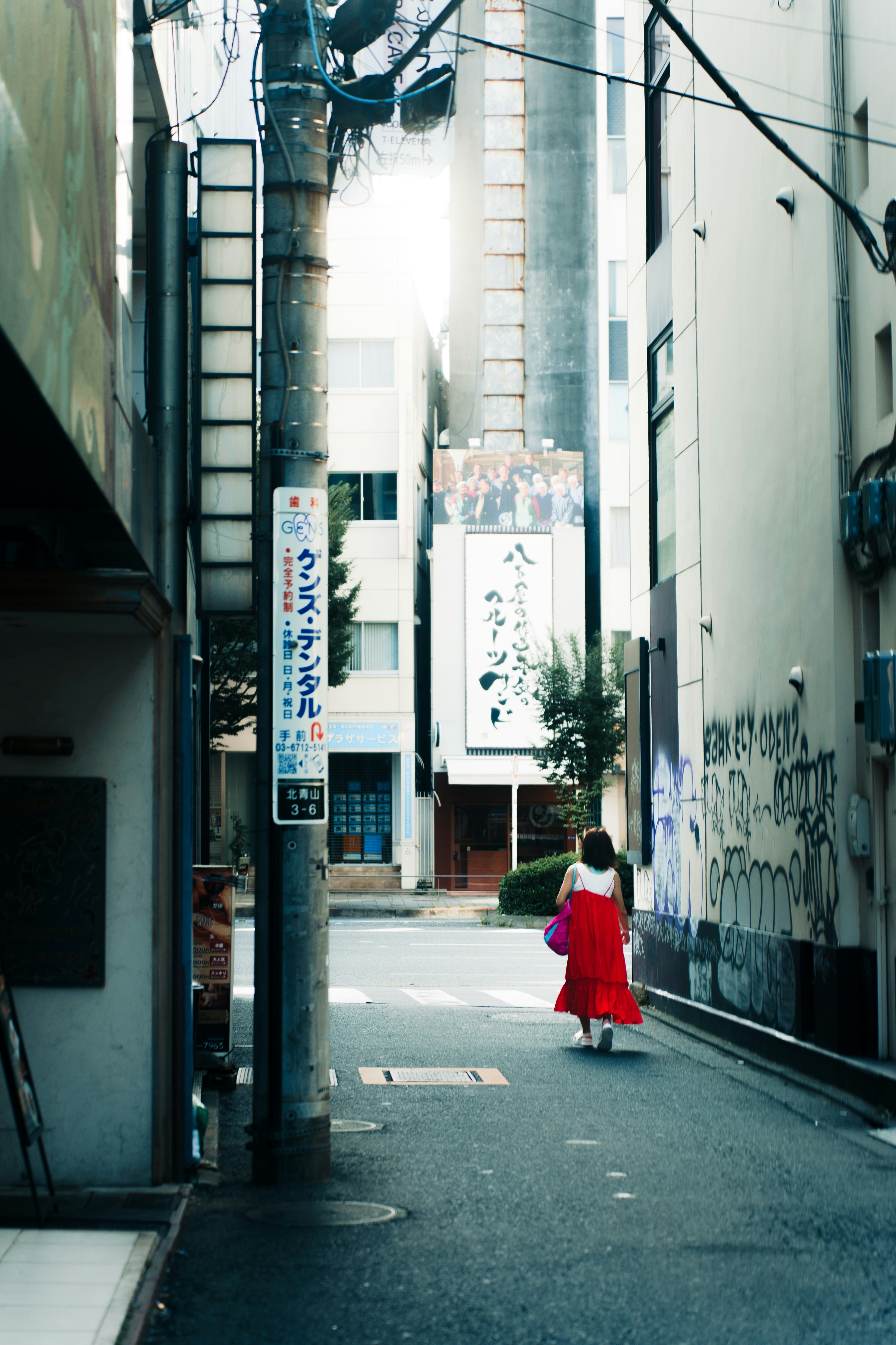 赤いドレスを着た女性が狭い路地を歩いている風景